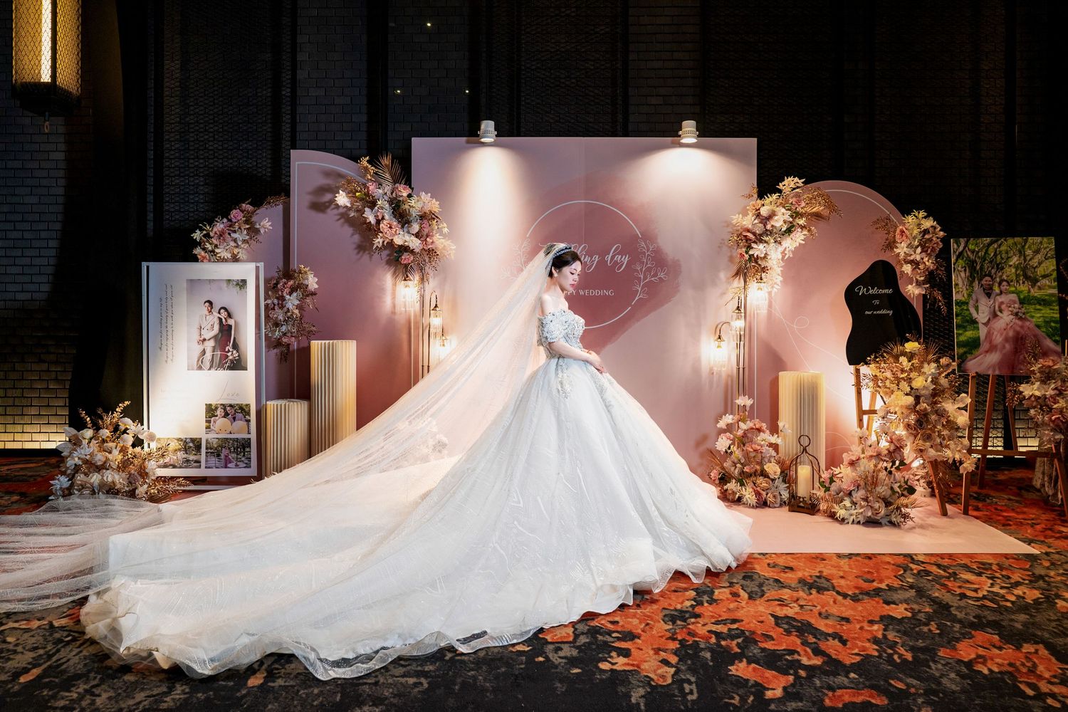 A stunning white wedding dress with a flowing train is displayed in a dimly lit venue with romantic floral decorations.