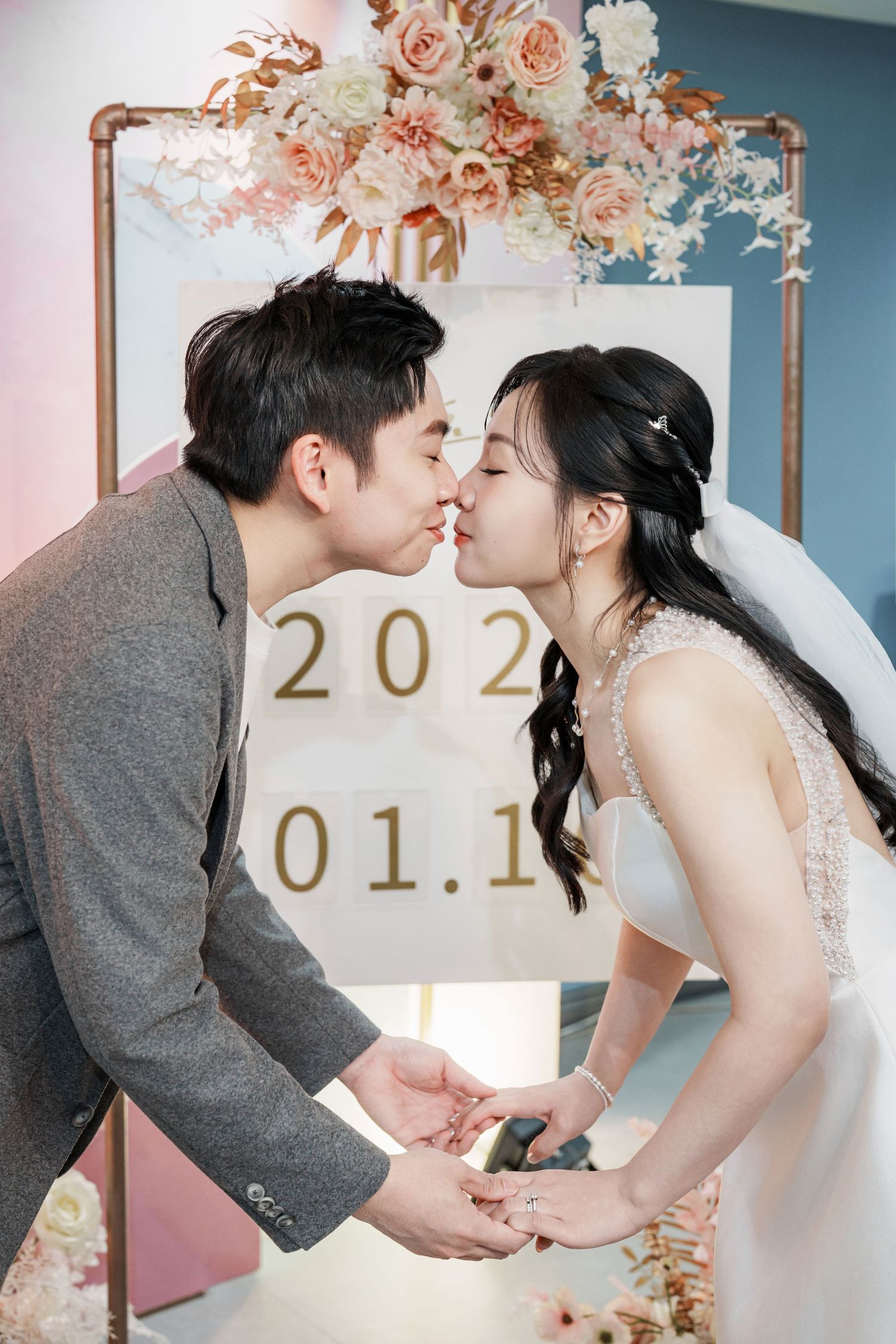 Romantic wedding photo series showing a couple in formal attire kissing against a blue wall with floral decorations and date numbers.