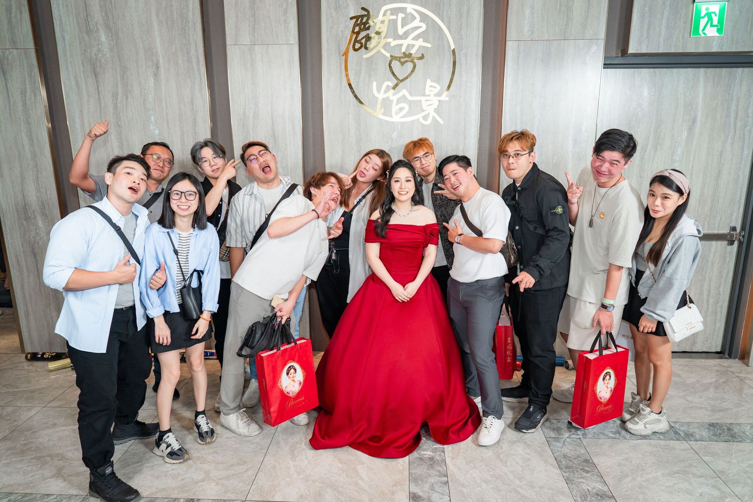 Wedding party members in red and white attire pose together against a wall for dynamic celebratory group photos.