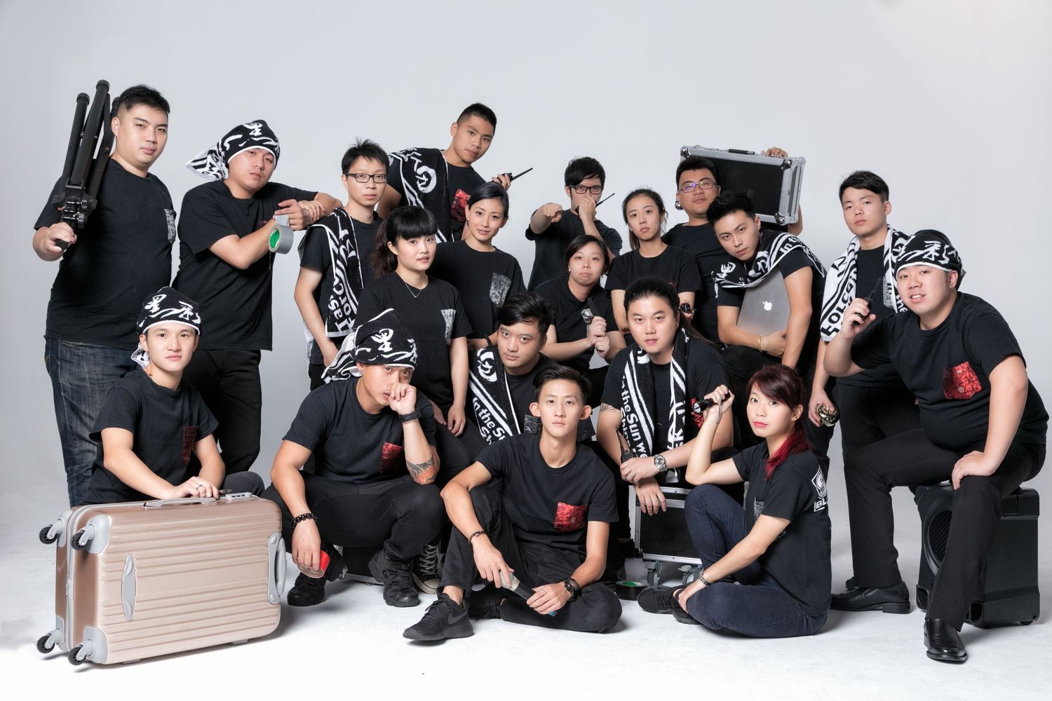 Large group of young Asian professionals in black uniforms posing together in a studio photo shoot.