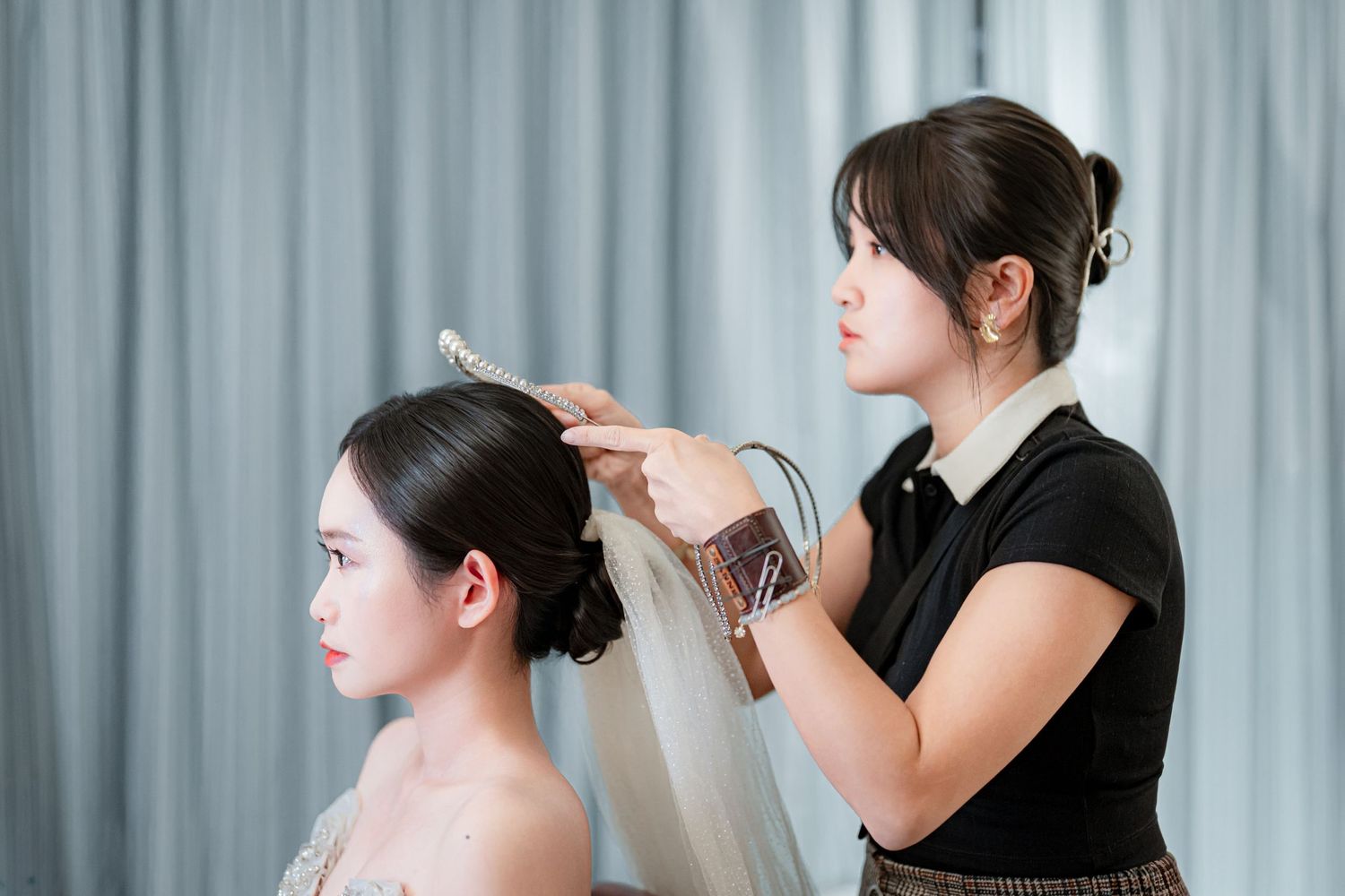 A series of four photos showing a stylist working on a model's hair and makeup for a professional beauty session.
