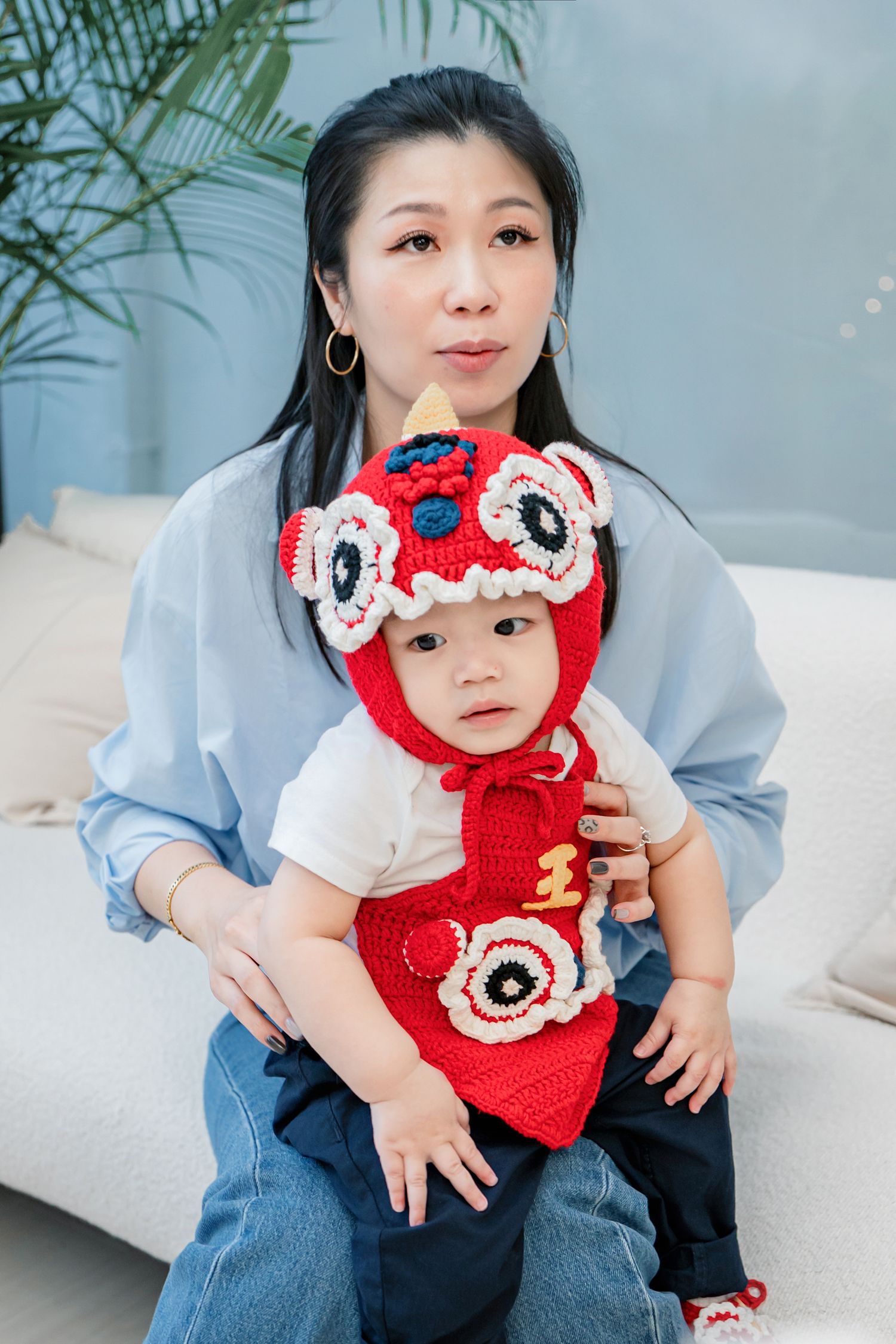 A series of photos showing a small child wearing a cute red knitted character hat and matching outfit on a couch.