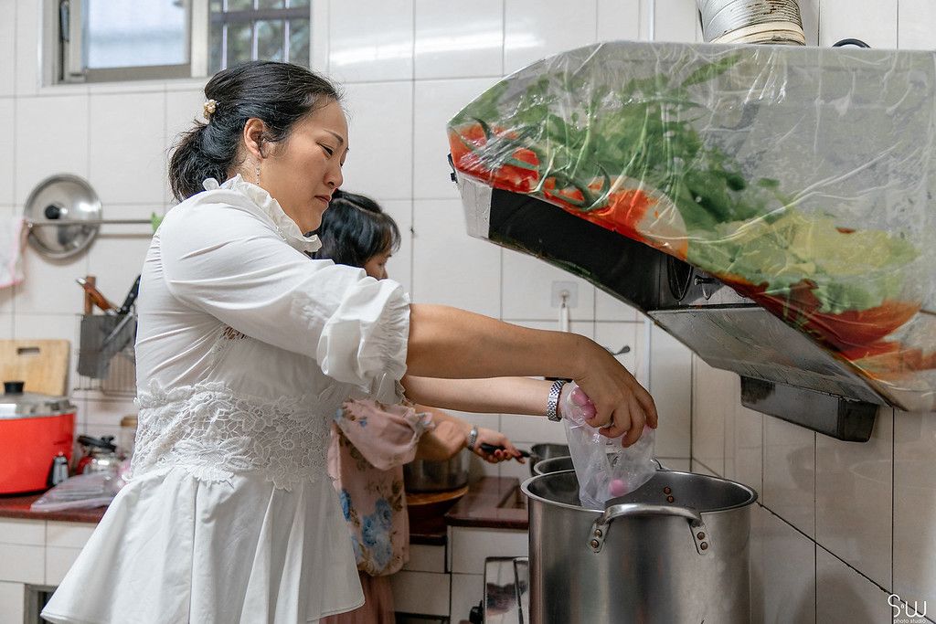 Someone in a white dress preparing food in a kitchen.