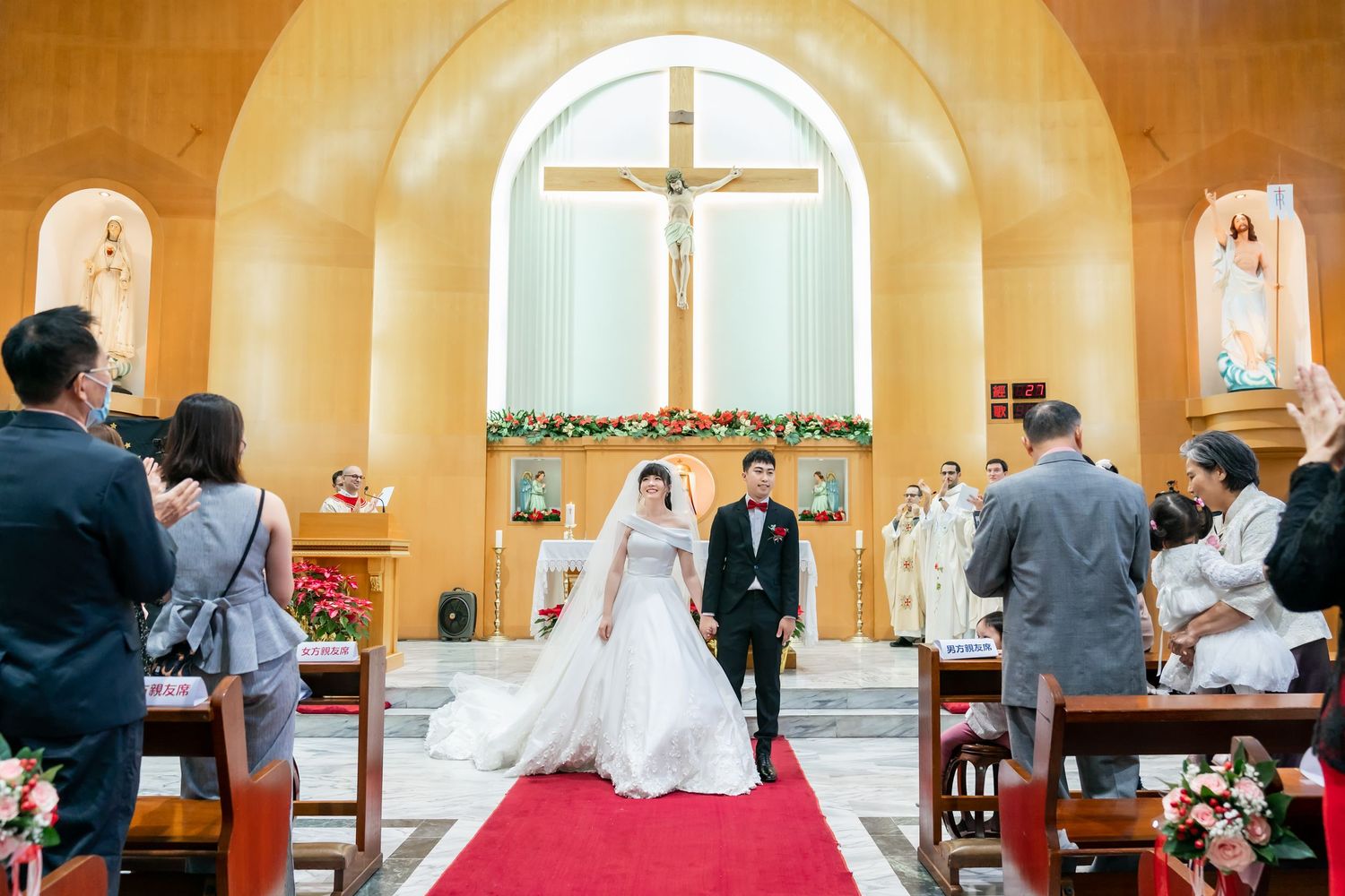 A couple walks down the red-carpeted church aisle after their wedding ceremony.