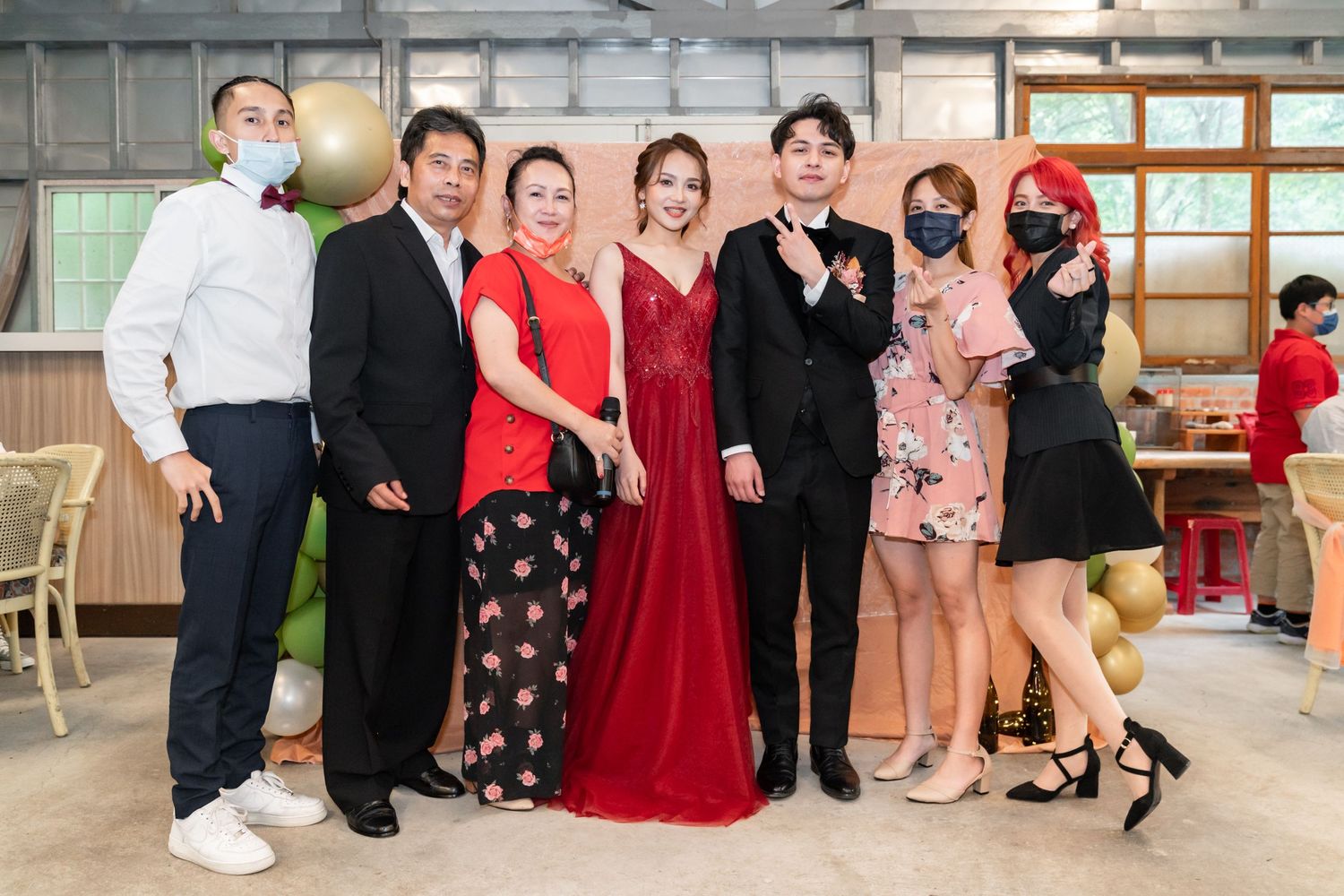 Event attendees in formal wear gather for a photo against an industrial backdrop.