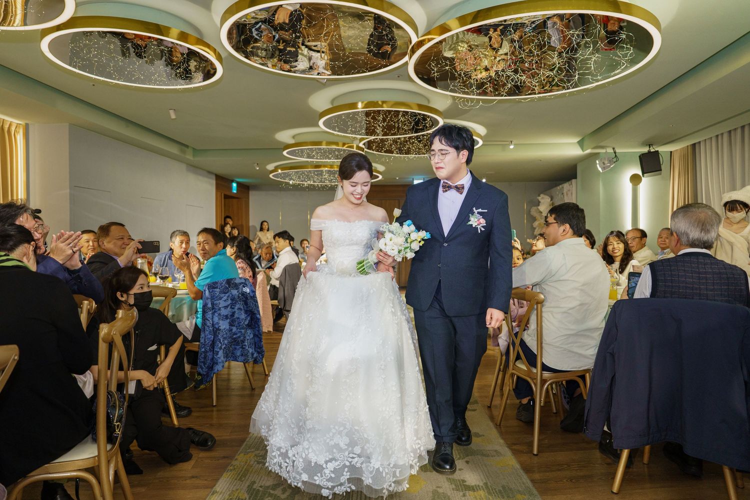 Elegant ballroom wedding reception with crystal chandeliers and circular ceiling details creates a romantic atmosphere.
