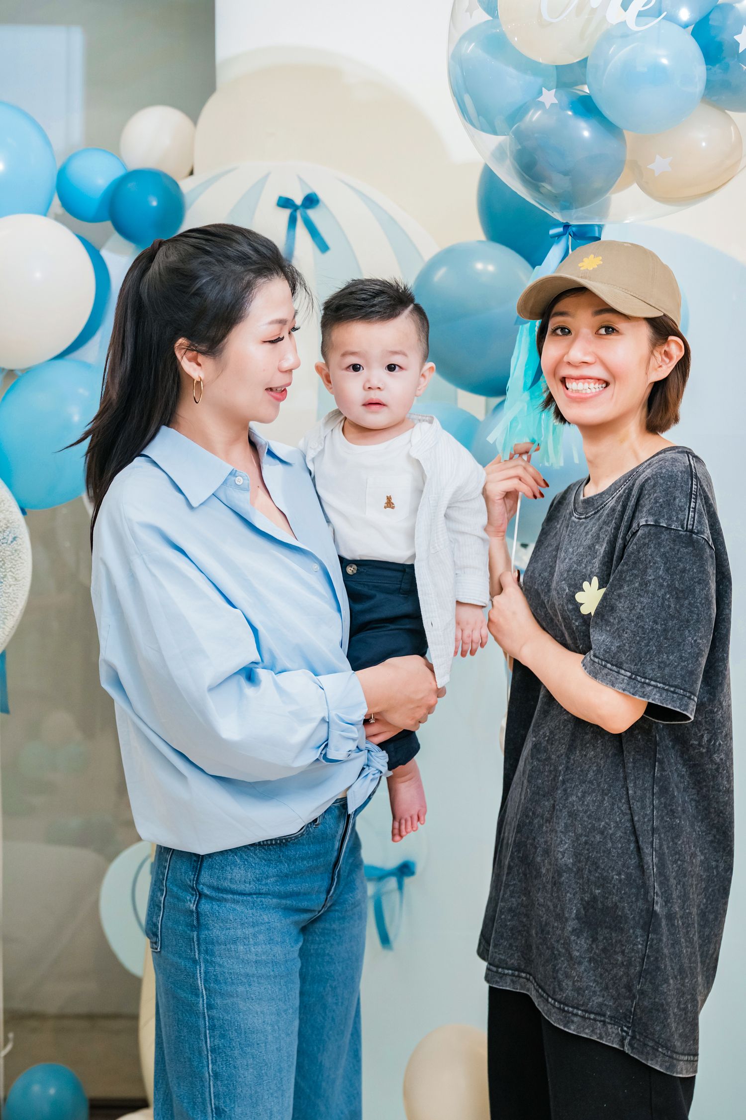 Family celebrating with blue and white balloons in a casual indoor photo session.