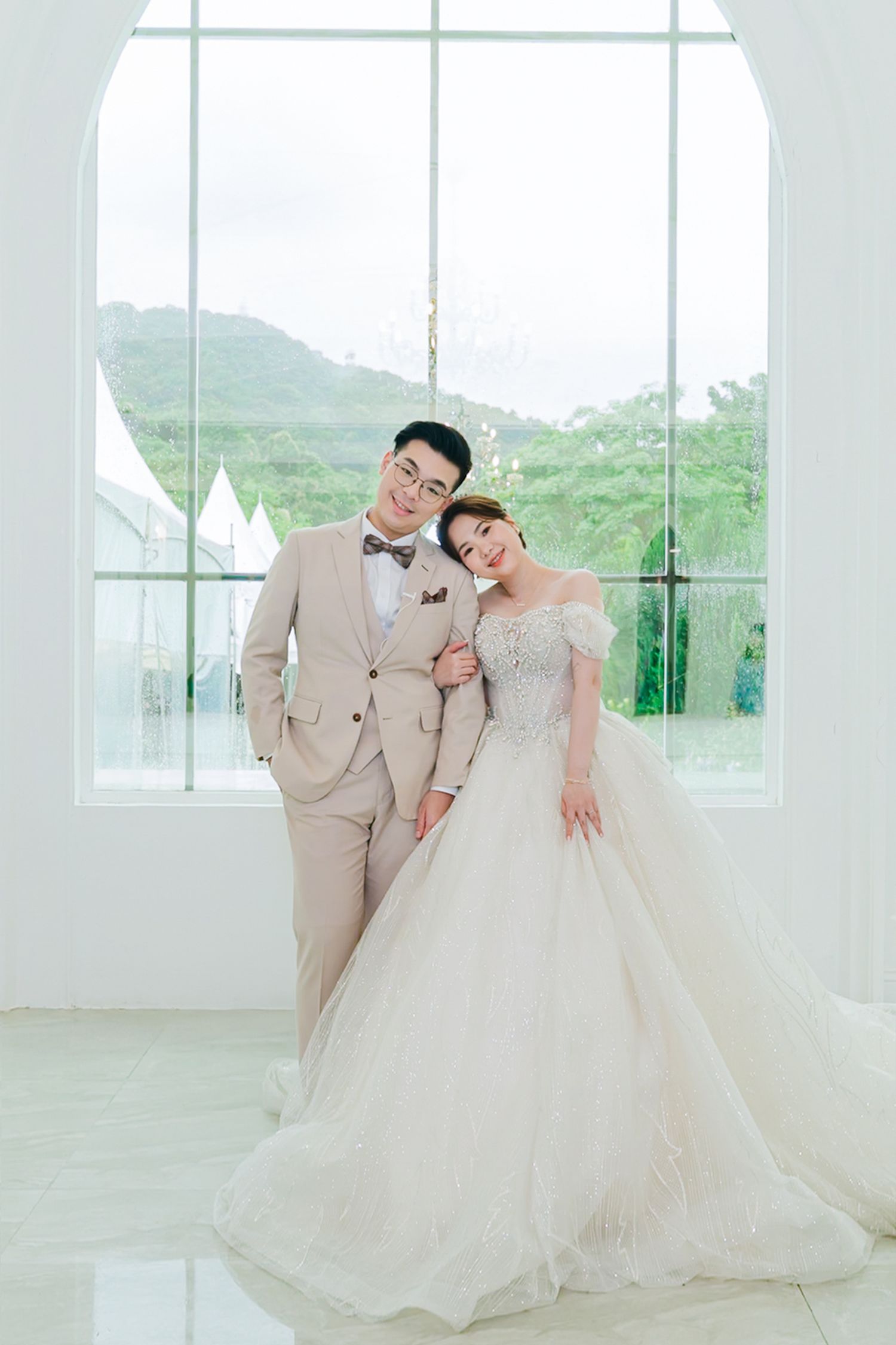 Elegant wedding photo series in a light-filled room showcasing couple in beige suit and flowing white gown.