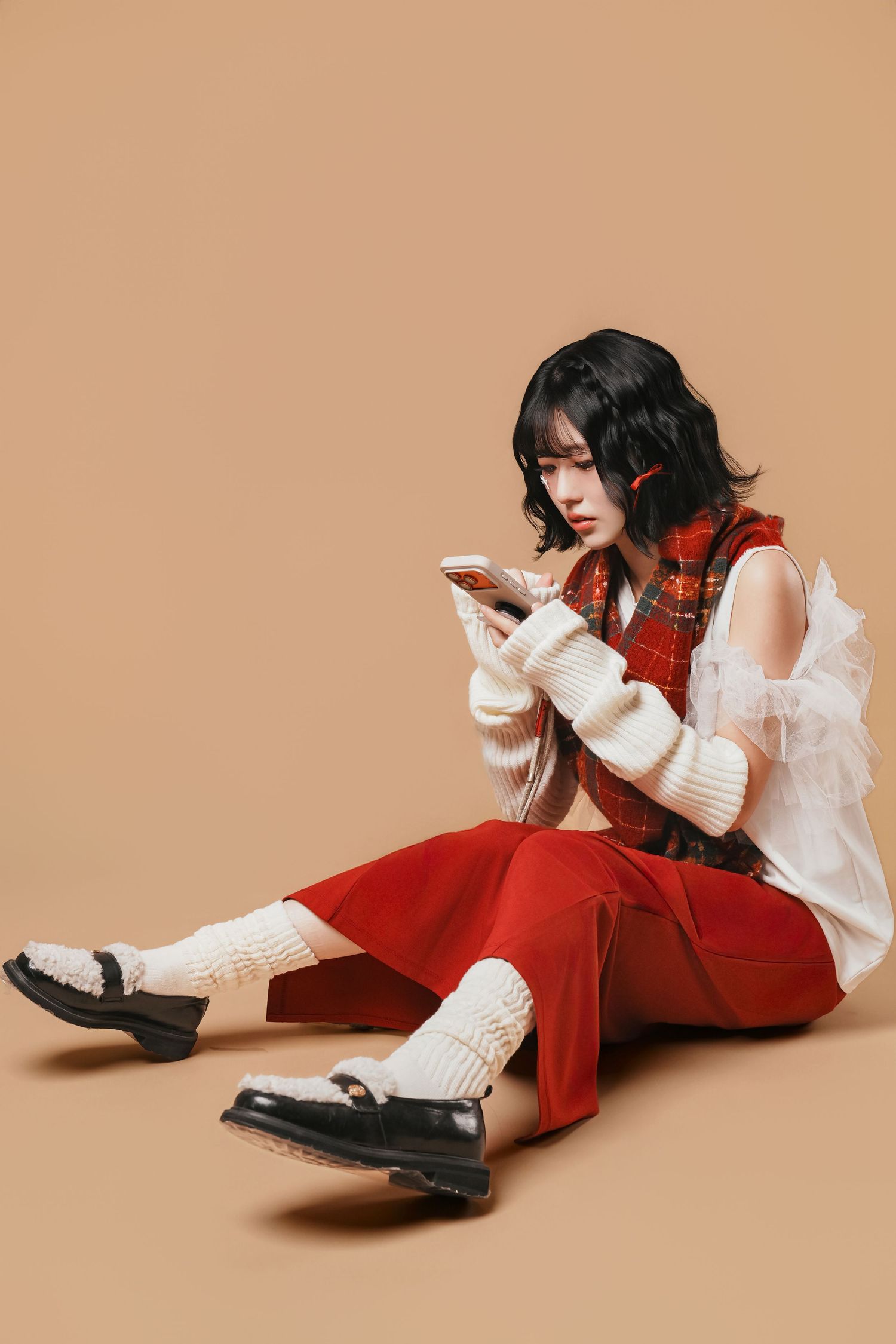 Person in red overalls and white blouse strikes dynamic poses against beige background in fashion photo series.