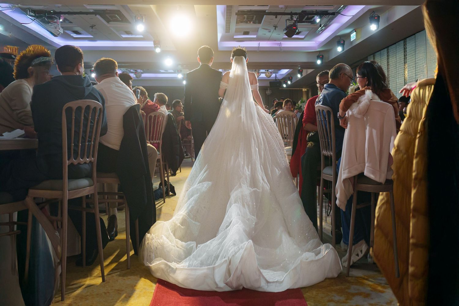 A wedding reception celebration with dancing guests and a bride in a flowing white gown on a dimly lit dance floor.