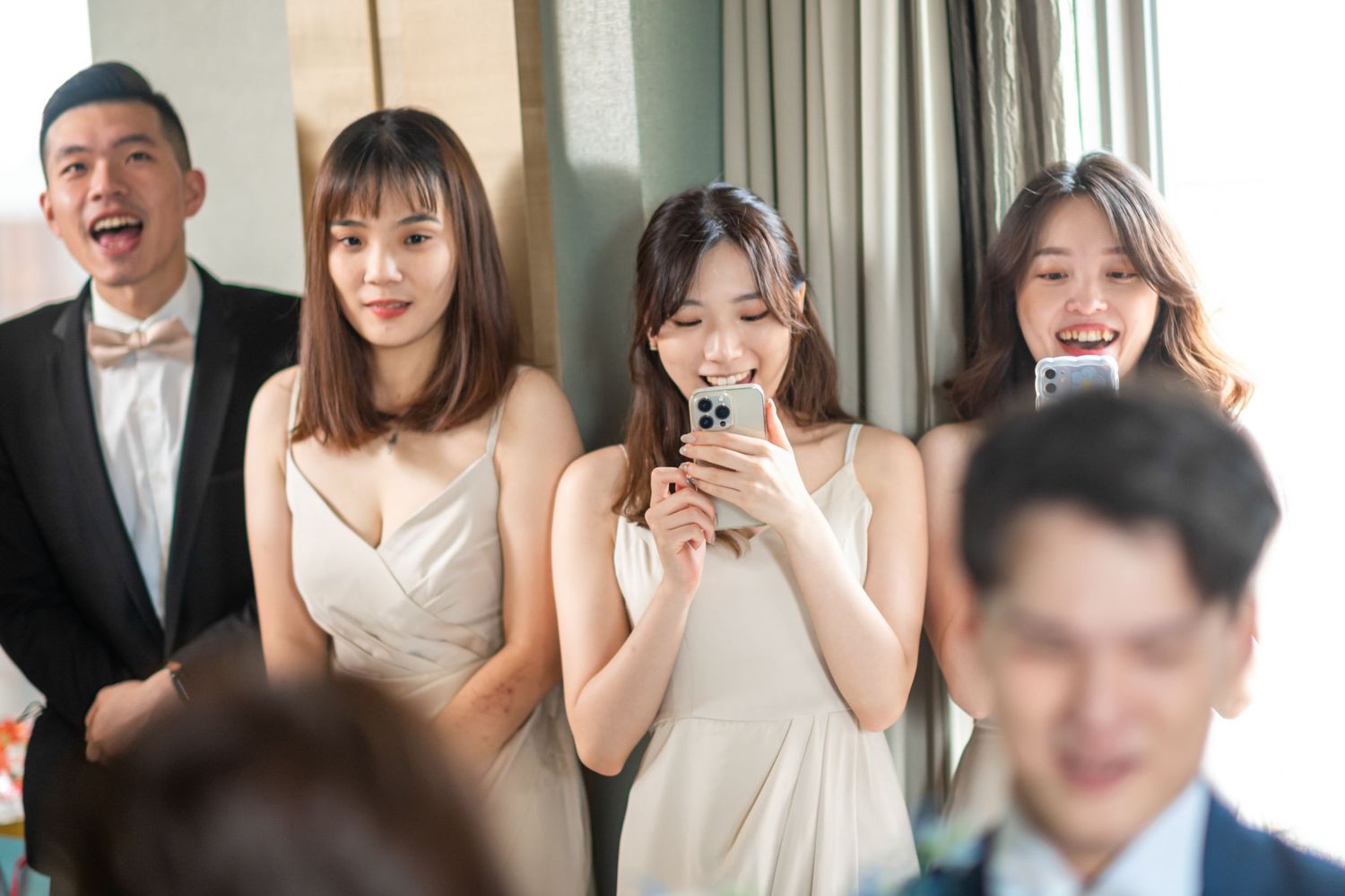 Wedding guests enjoying themselves at a celebration while smiling and raising their glasses for a toast.