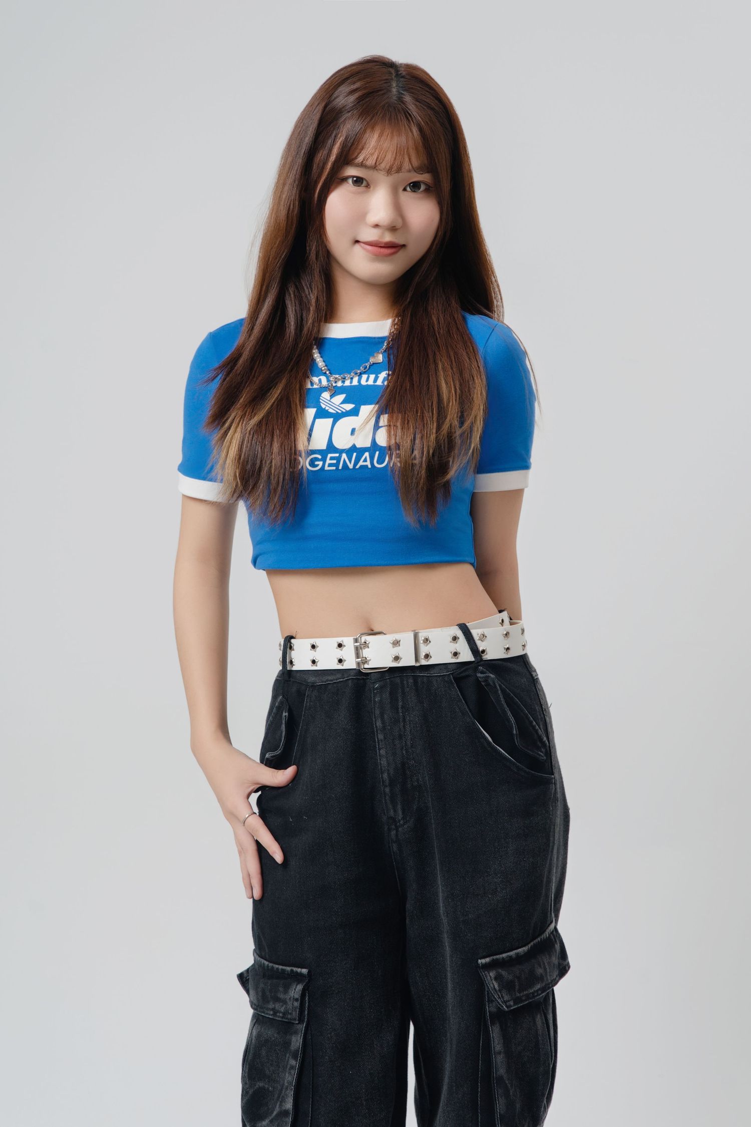 Young woman in blue crop top and black cargo pants poses against white background in three similar fashion shots.