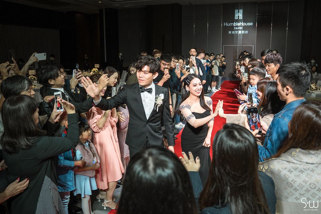 Wedding reception scene with guests capturing the celebration on their phones.