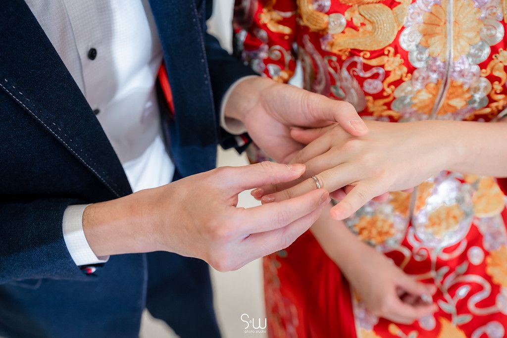 Close-up shot of wedding ring exchange with bride in traditional Chinese dress.
