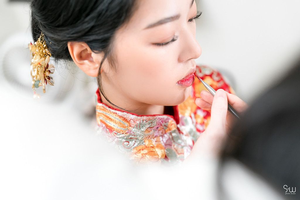Close up of someone having lipstick applied while wearing an ornate gold hair accessory.