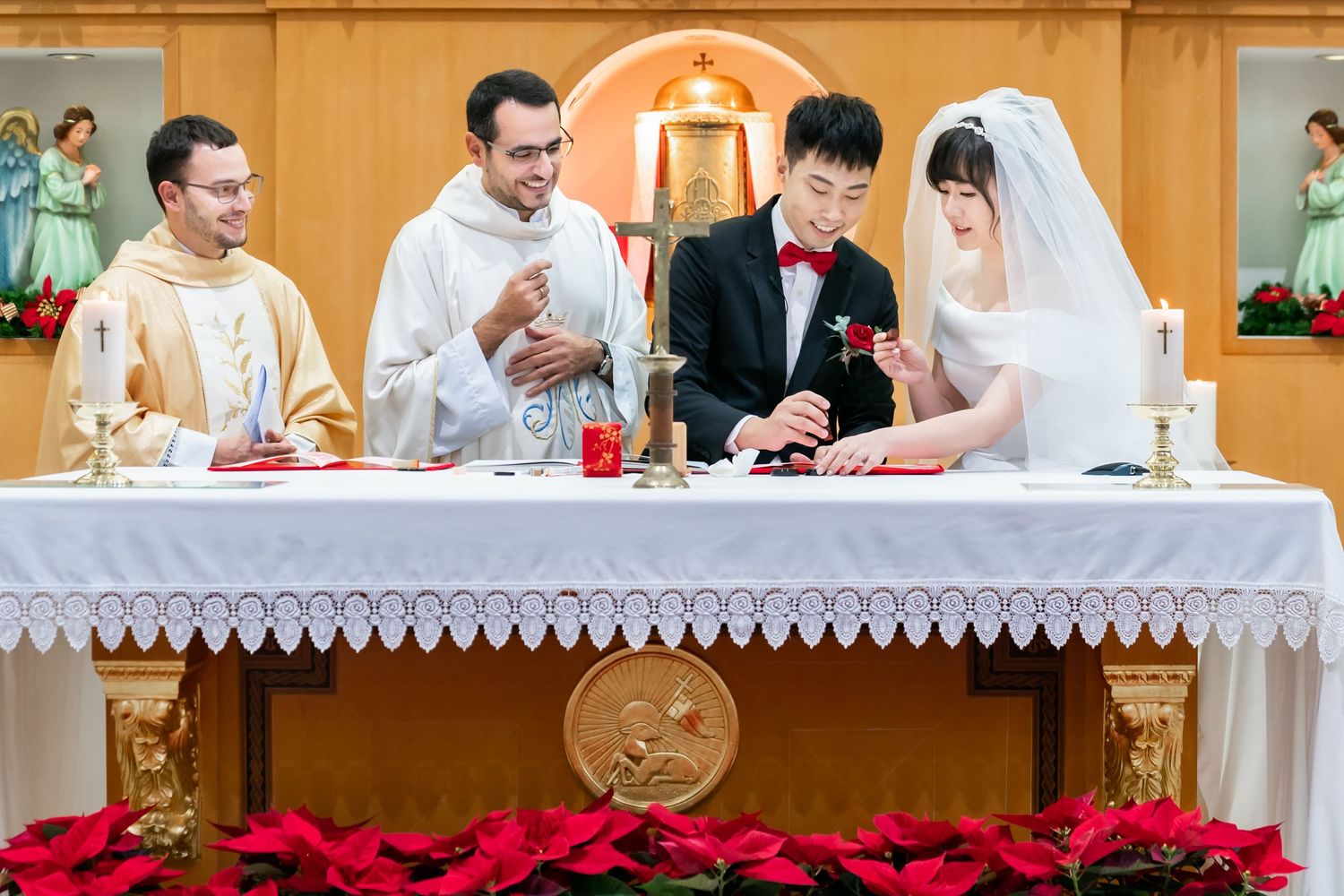 Wedding ceremony participants gathered at altar table with priests during Catholic mass.