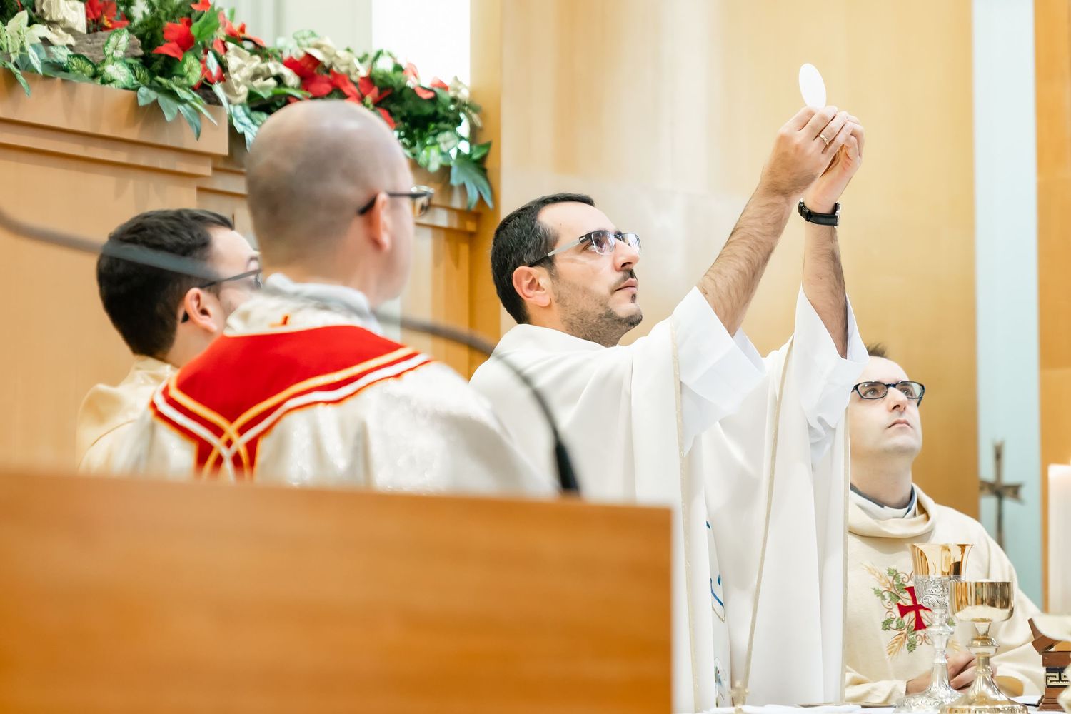 Priests in white robes perform religious ceremony at decorated church altar.