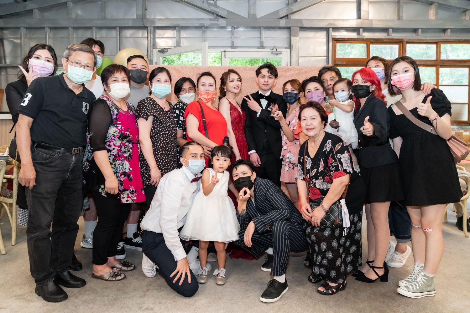 Large group gathered for a celebratory event in an industrial-style venue with high ceilings.