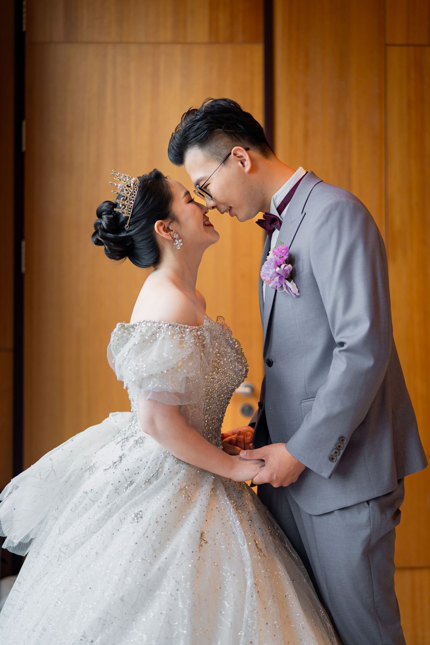 The newlyweds share an intimate moment against a wooden backdrop, with the bride in a beaded ballgown.