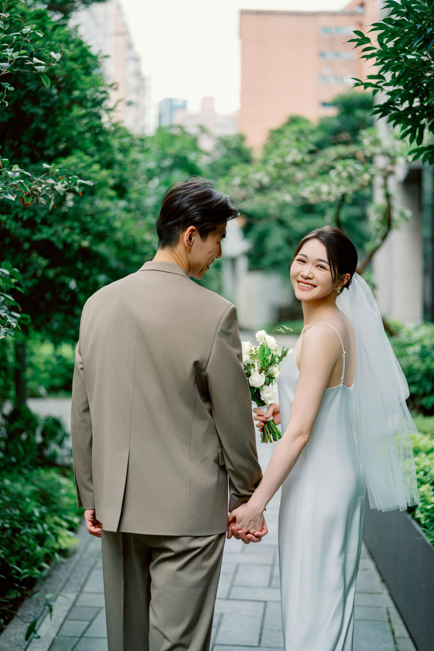 Newlywed couple walks along a garden pathway in a series of romantic wedding photos showing their interactions together.
