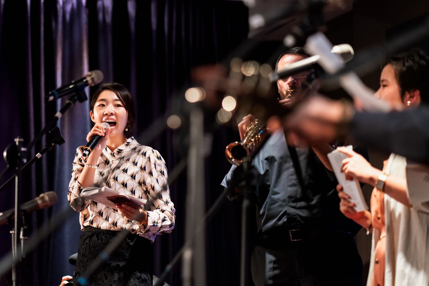 Musicians perform on stage with microphones and instruments at an event.