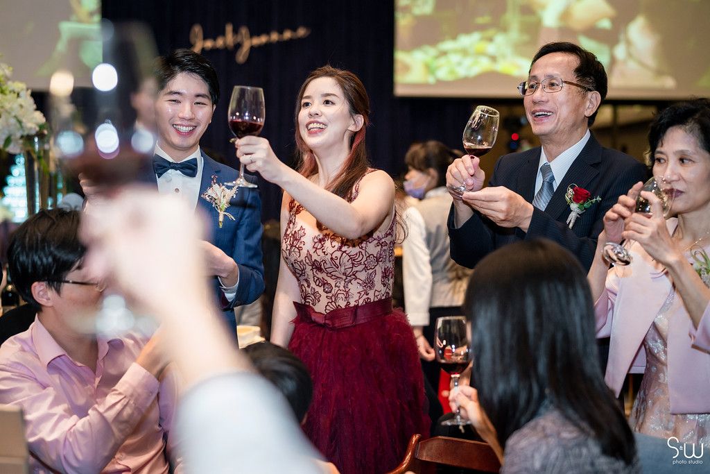 Wedding reception guests raise wine glasses in a celebratory toast.