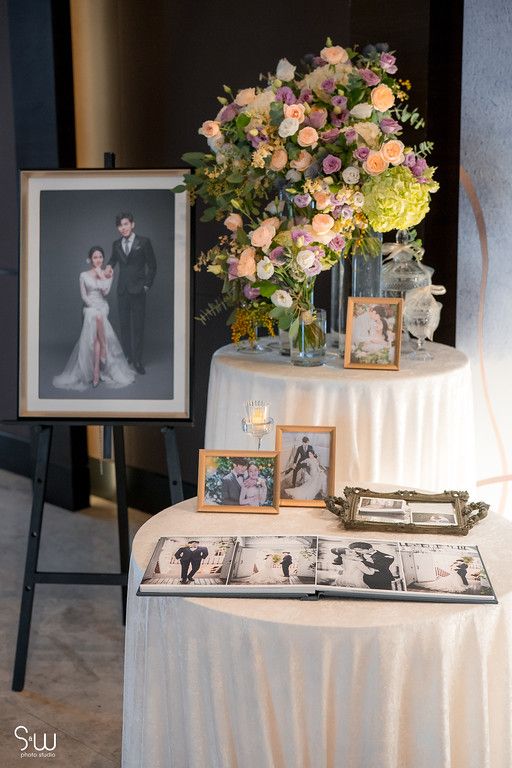 Wedding memory table with framed photographs and floral arrangements in peach and pink tones.