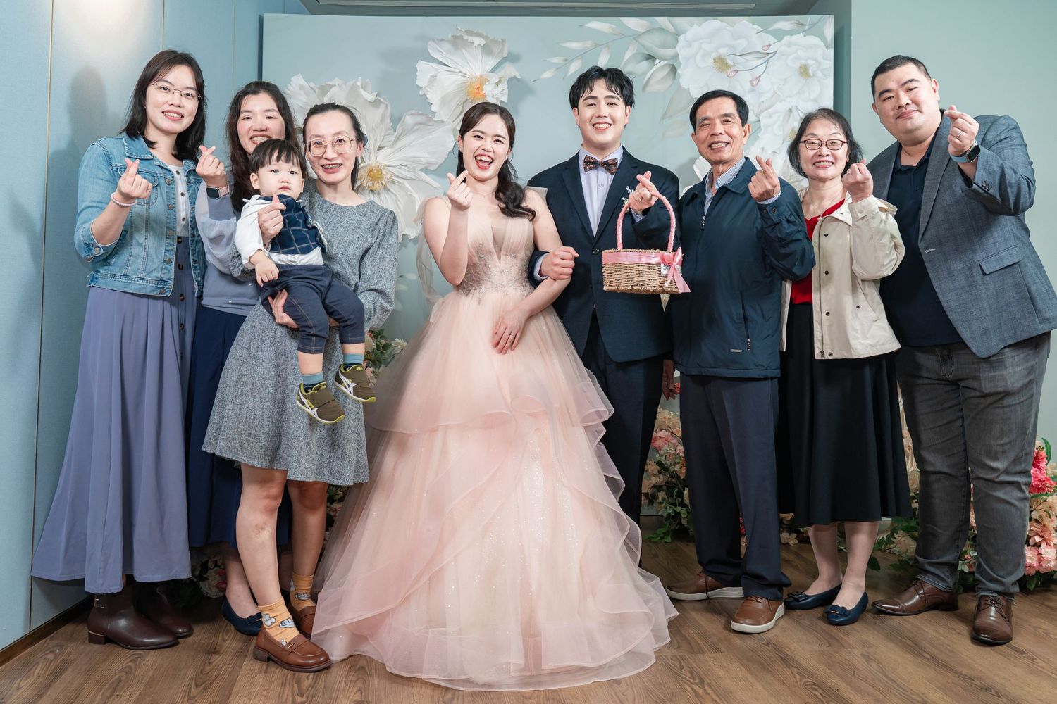 Wedding party members in blue and pink formal attire pose together in a joyful celebration atmosphere.