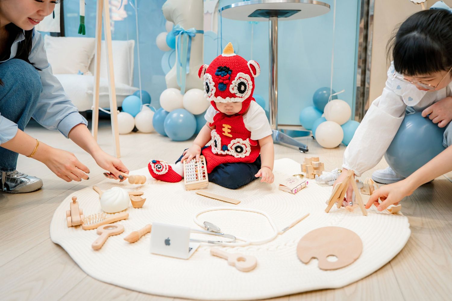 A series of hands kneading dough on a white surface with a red plush toy in the background.