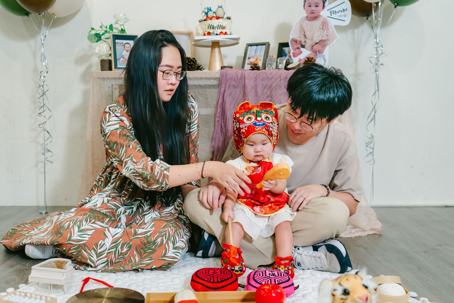 A family celebrates a birthday with party hats and cake at a minimalist decorated white table setting.