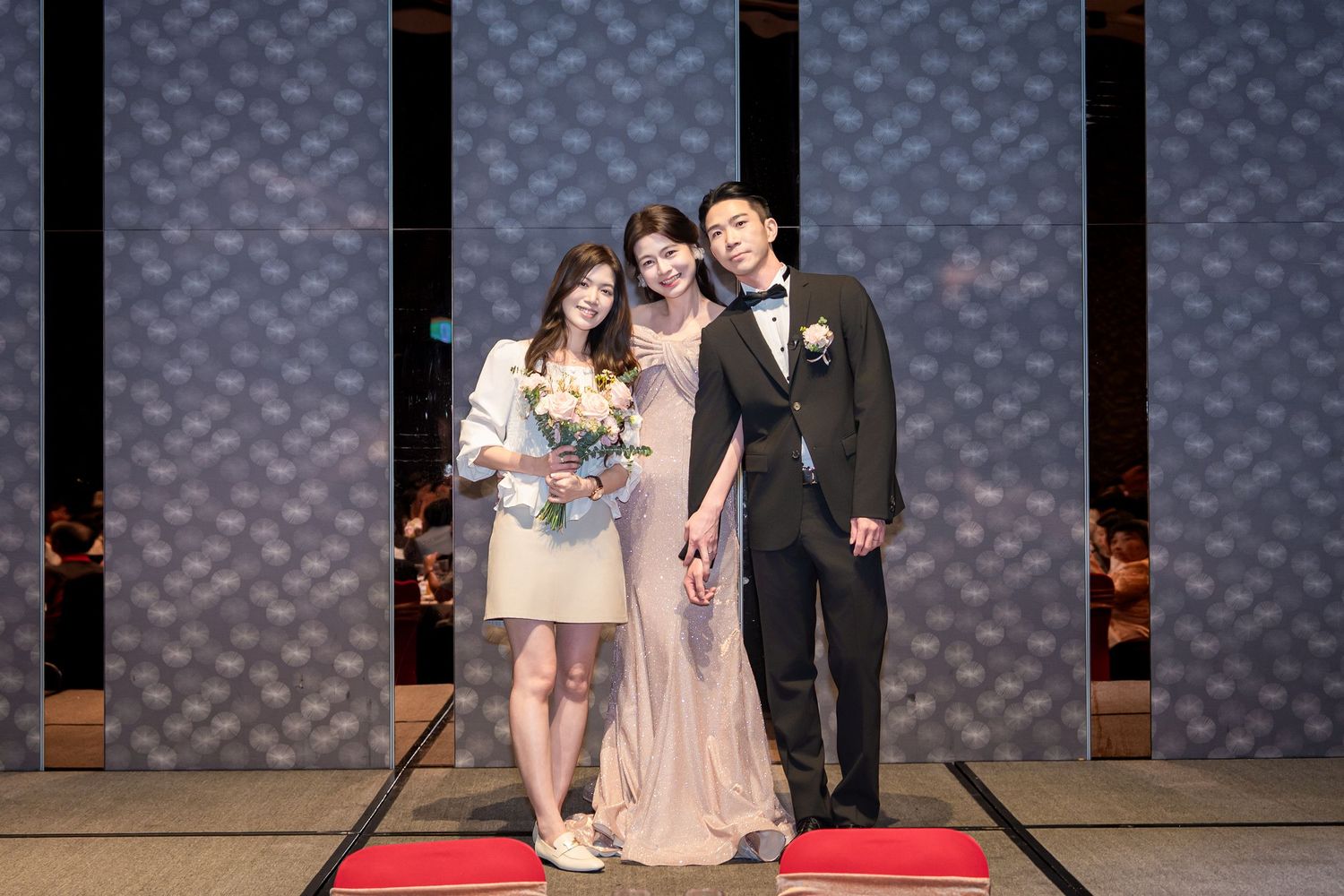 Wedding party stands in a row on stage with twinkle lights in the background during formal ceremony.
