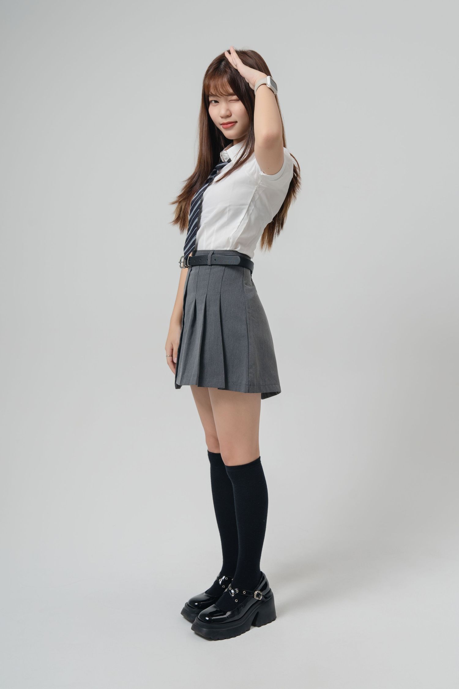 Four fashion poses showing a gray pleated skirt outfit with black knee-high socks and white top against a light background.