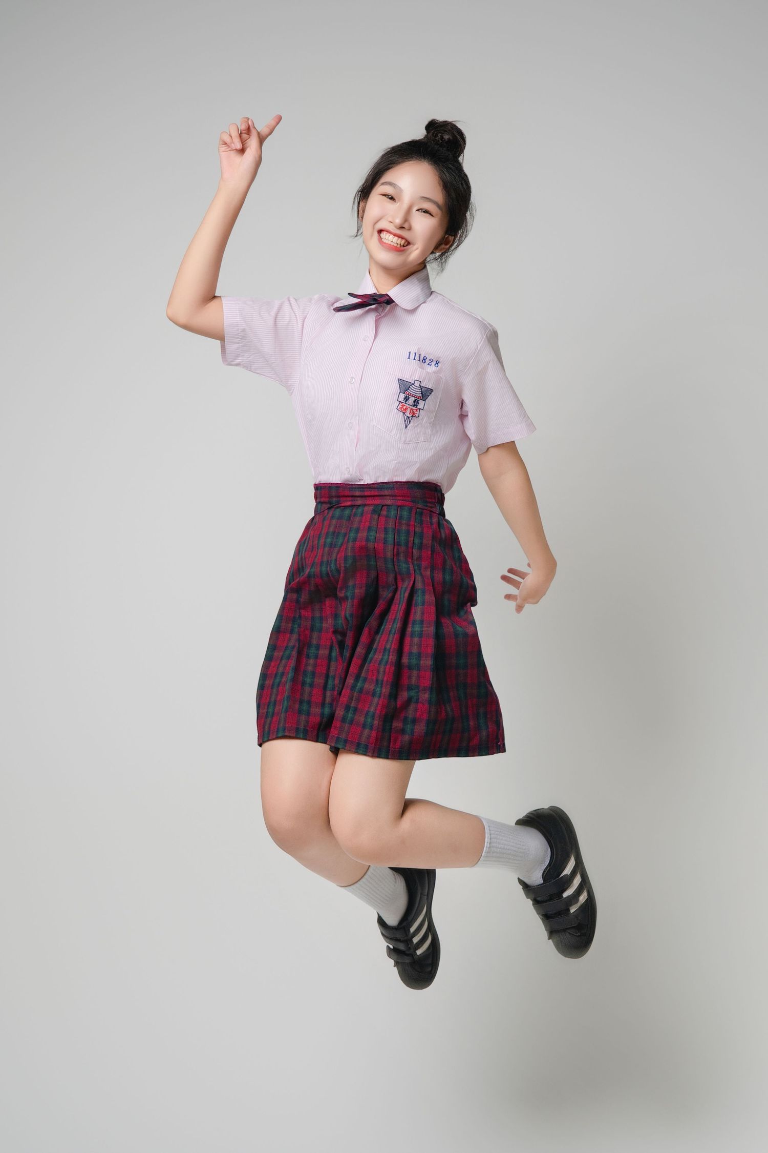 A person in a plaid skirt and white top jumps playfully against a white background in a series of action shots.