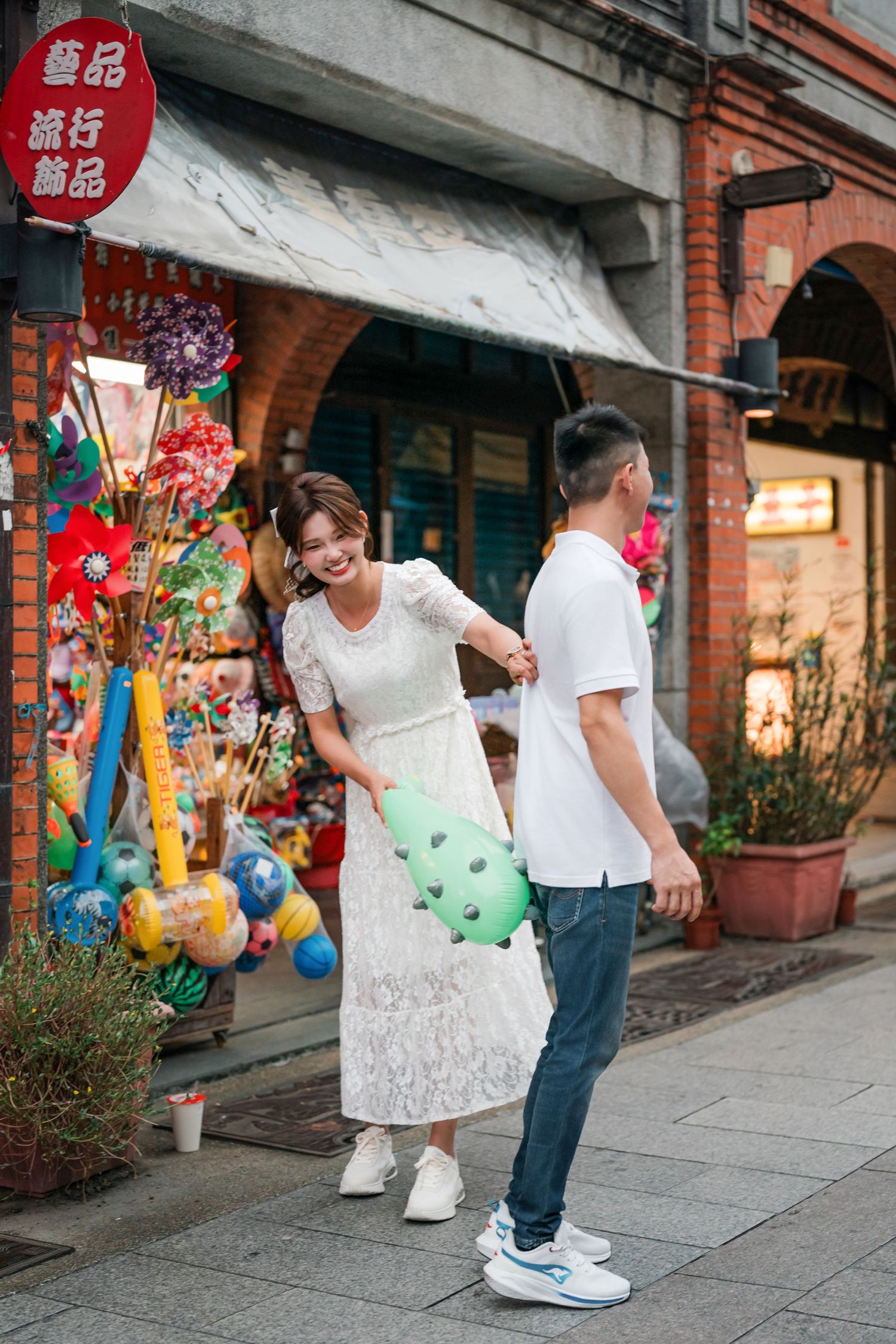People enjoying a colorful shopping street in Taiwan with hanging decorations and storefronts visible.