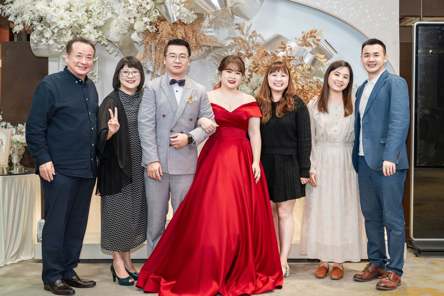 A group of people pose at a formal event with a person in a stunning red ball gown as the centerpiece.
