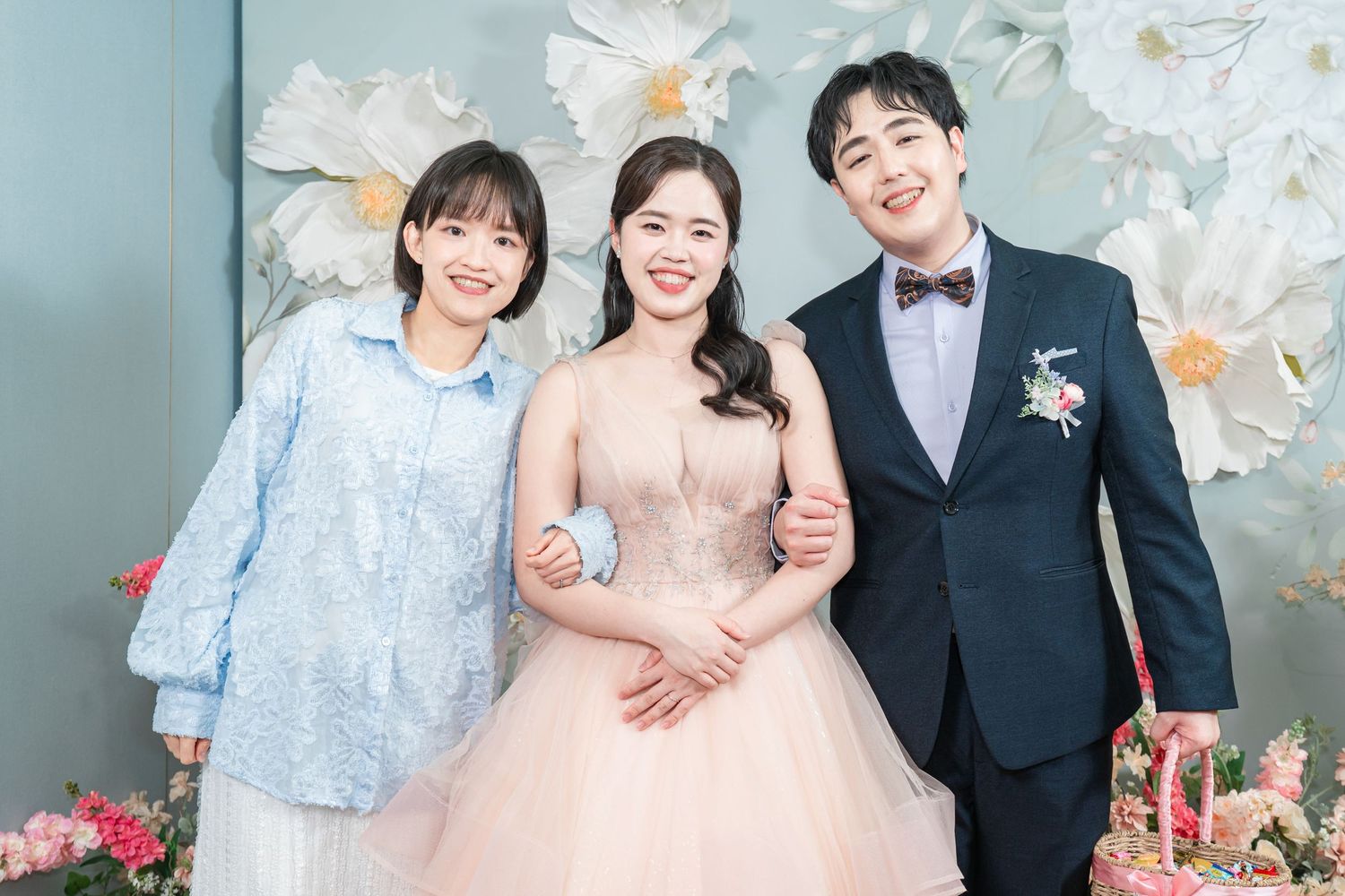 A wedding celebration scene with floral decorations and formal attire against a soft gray backdrop.