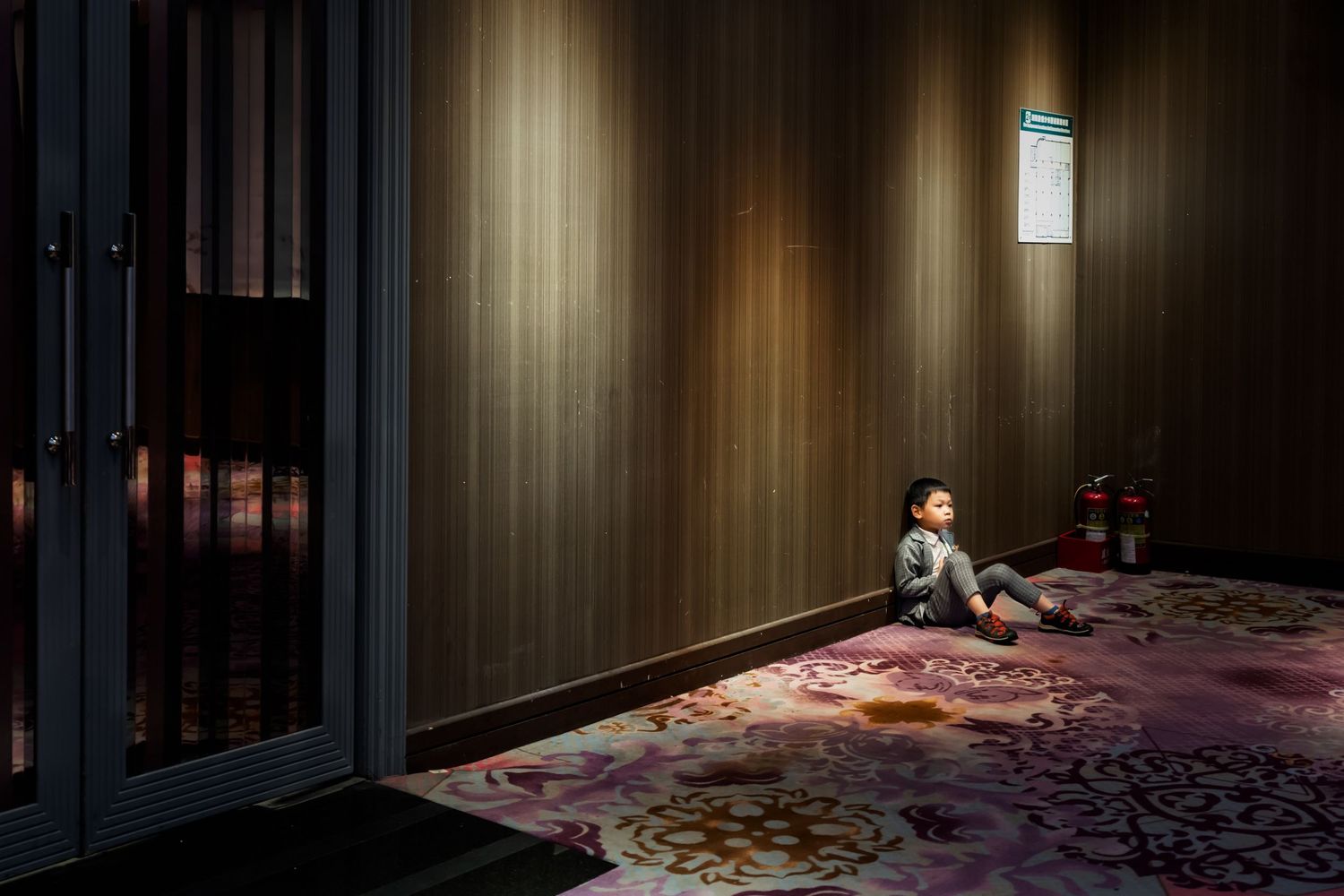 A dimly lit room with ornate carpet and wood paneling creates a moody atmosphere.