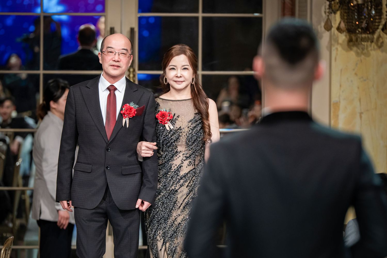 Wedding party members dance and celebrate during an evening reception in an elegant ballroom setting.