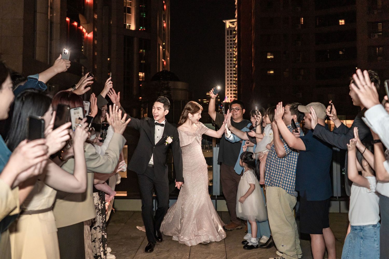 Several people dancing and raising their hands during a party or celebration event with mood lighting.