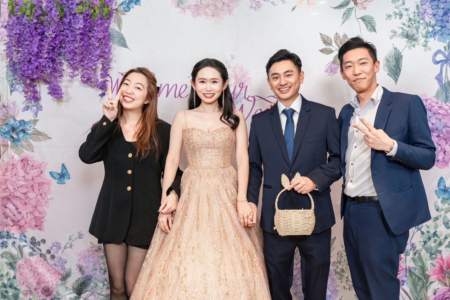Group of people posing together at a formal event with floral decorations in the background.
