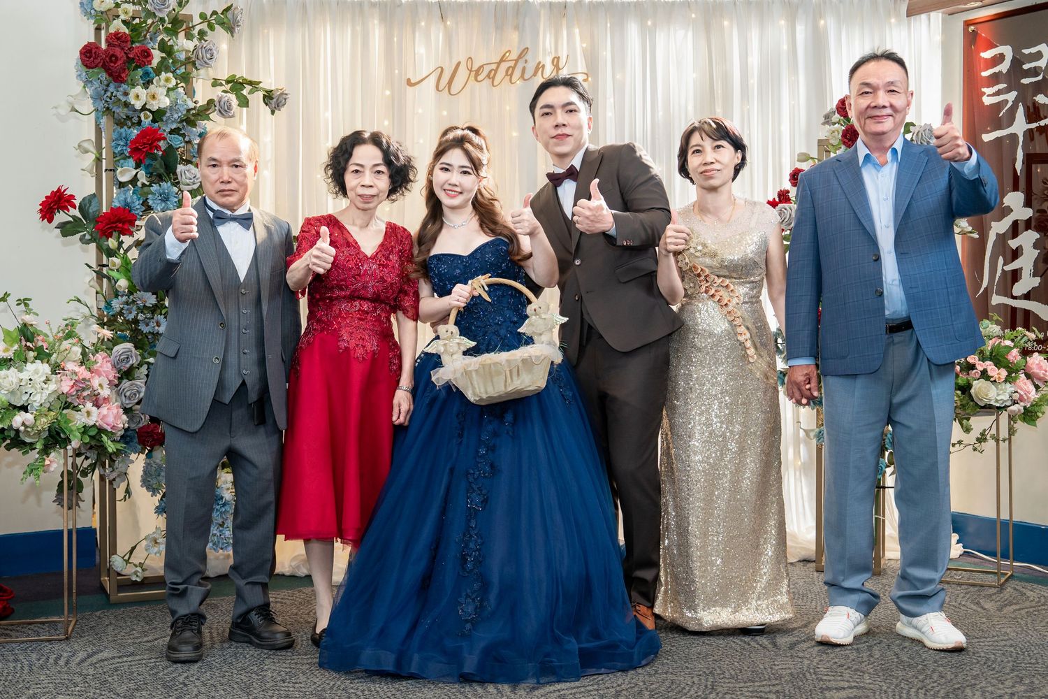 Wedding guests pose together in elegant navy blue and champagne colored formal attire at an indoor reception venue.