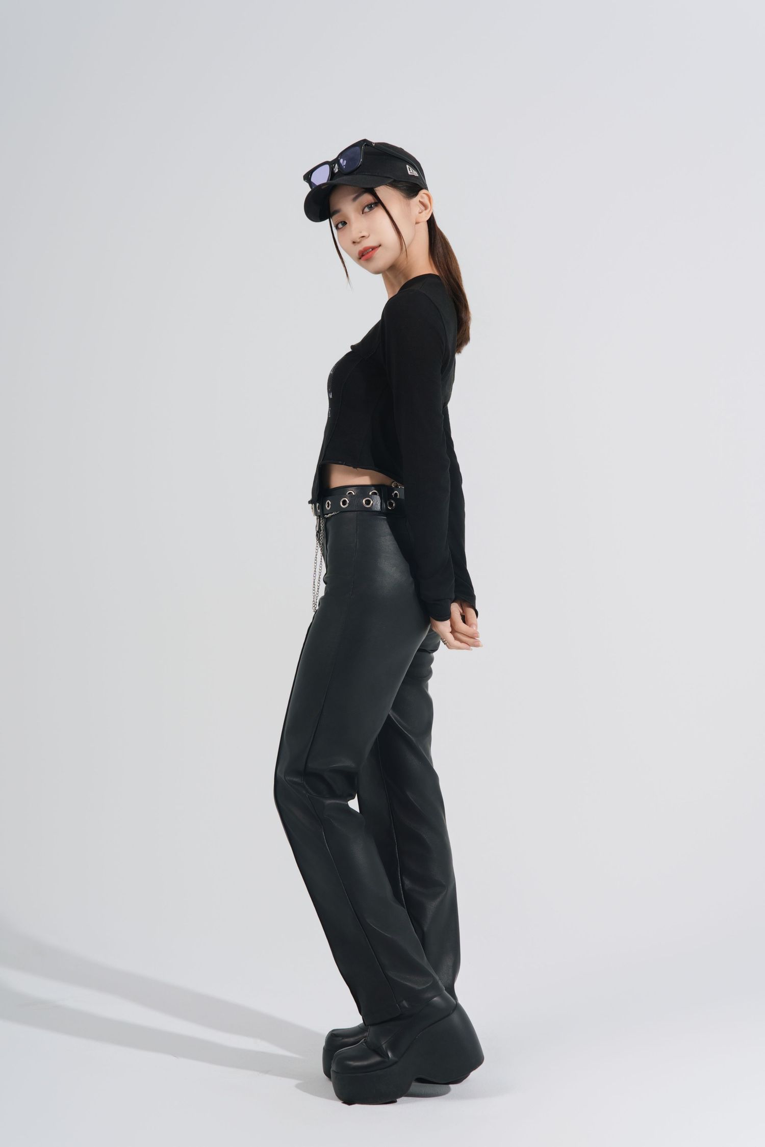 A fashion model wearing all black streetwear poses in different angles against a white studio backdrop.