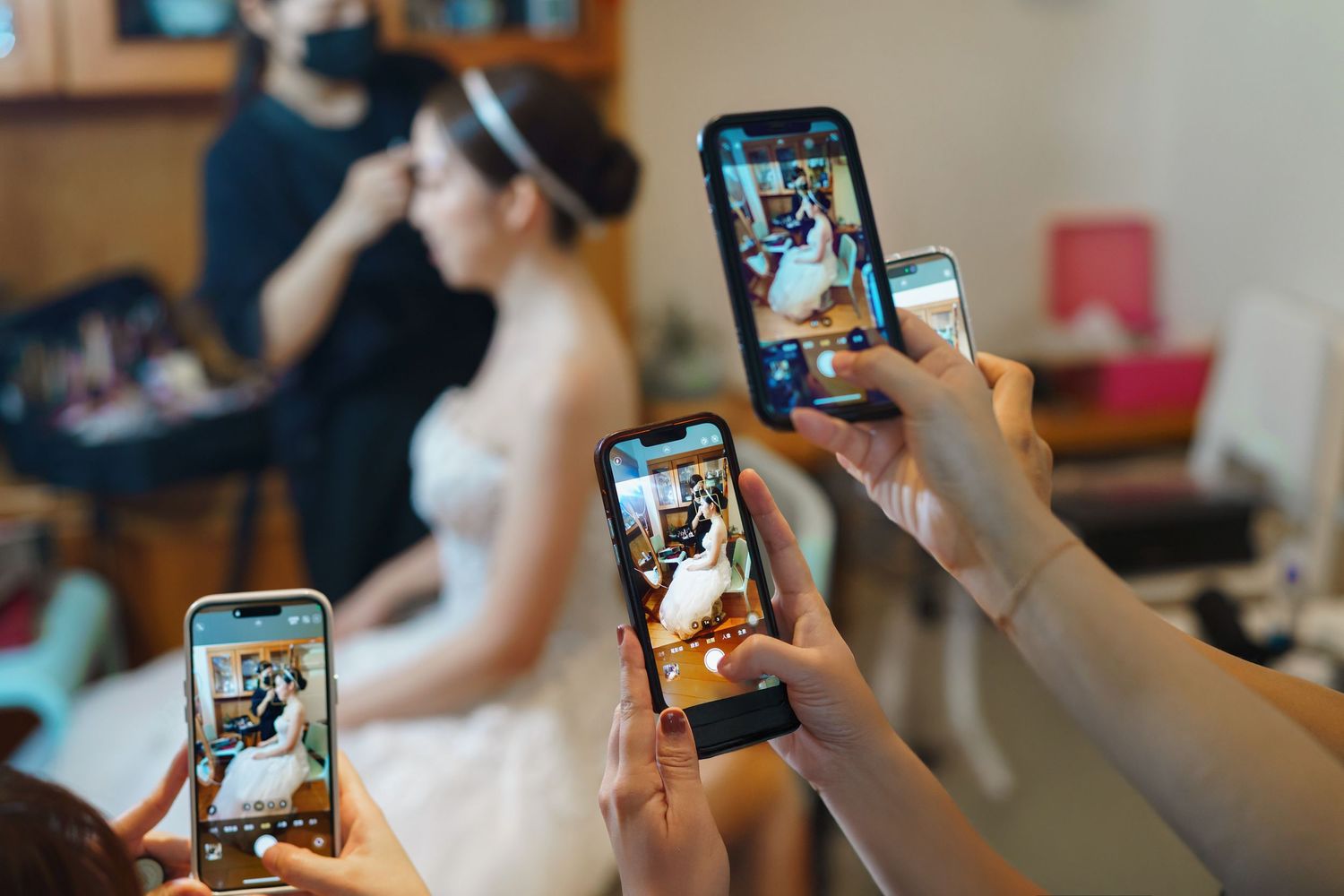 Multiple hands hold smartphones to capture photos of a special moment being prepared in a salon setting.