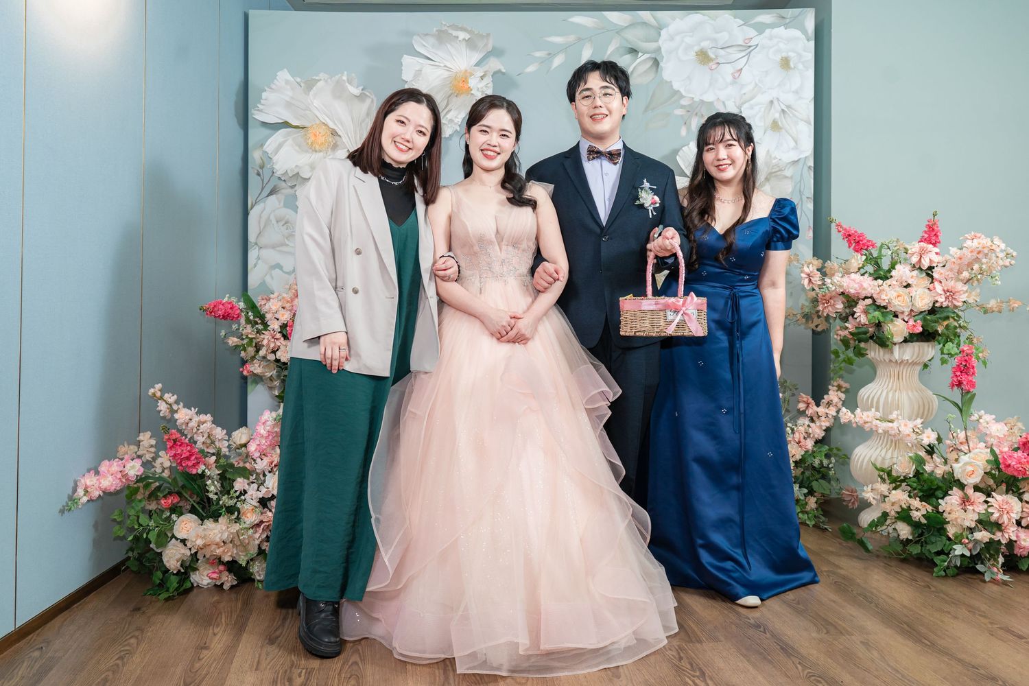Wedding party poses in front of floral backdrop in formal attire at elegant celebration.