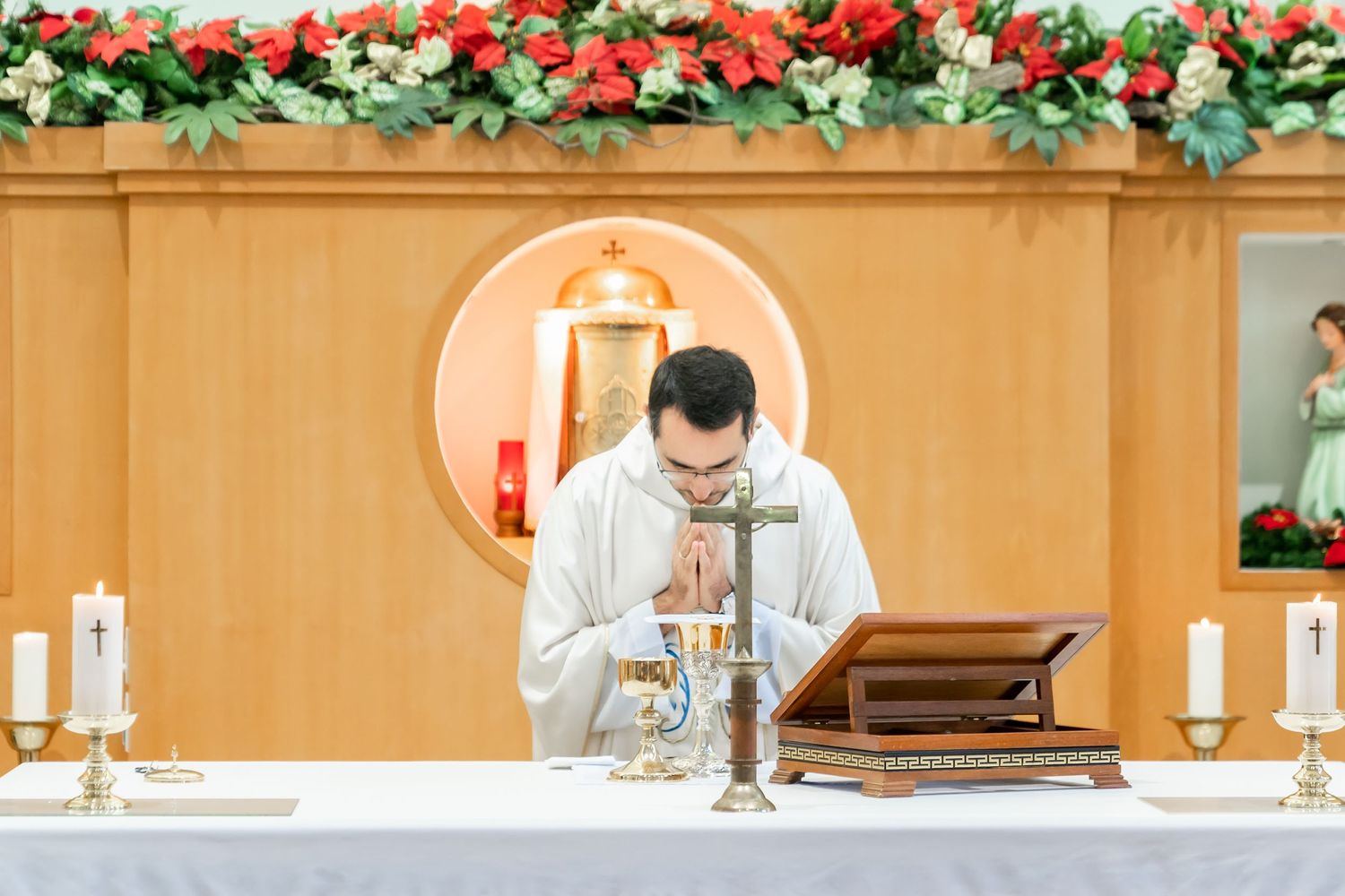 Priest conducting a sacred ritual at an altar adorned with floral decorations.