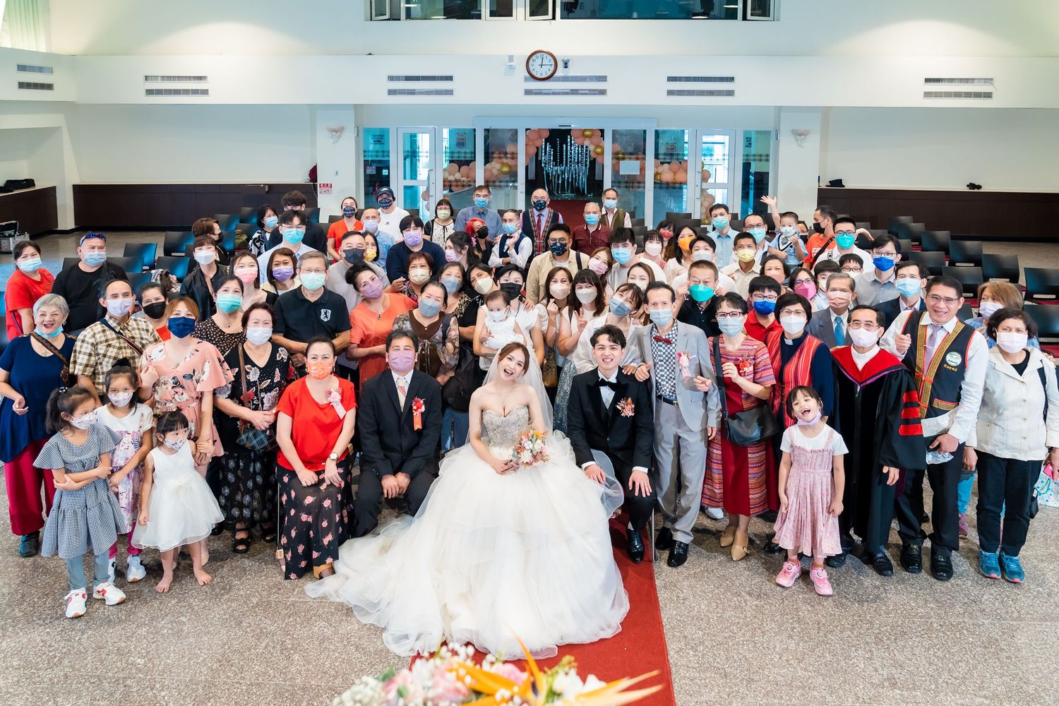 Wedding celebration group photo showing many guests standing together in church reception area.