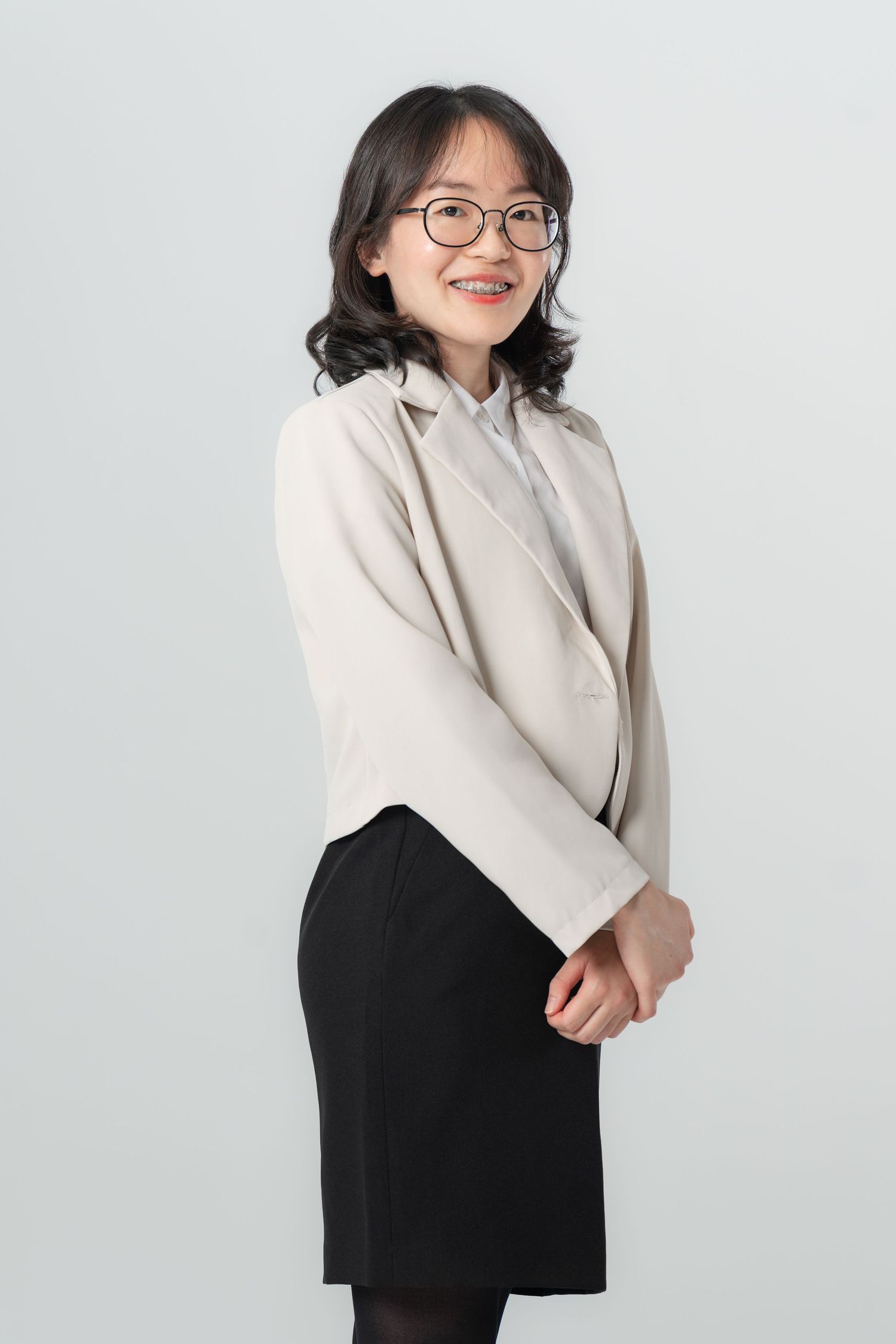 Professional portrait of someone wearing a beige blazer and black skirt in various casual poses against a white backdrop.