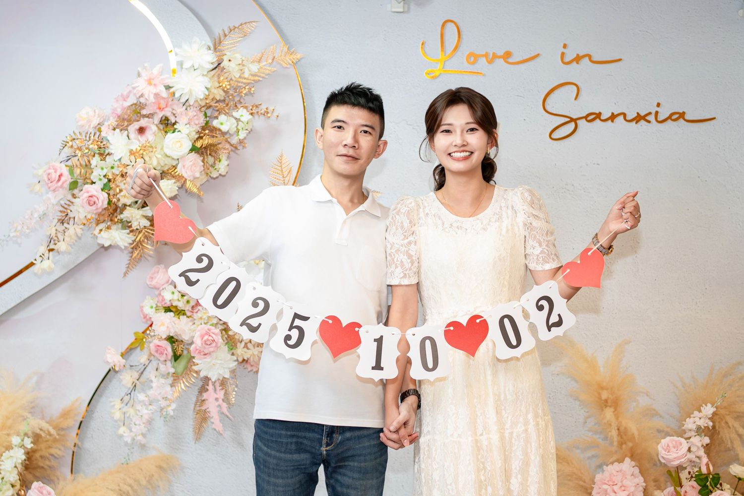 A romantic wedding photoshoot setup with floral decorations, heart symbols, and soft lighting in pastel colors.