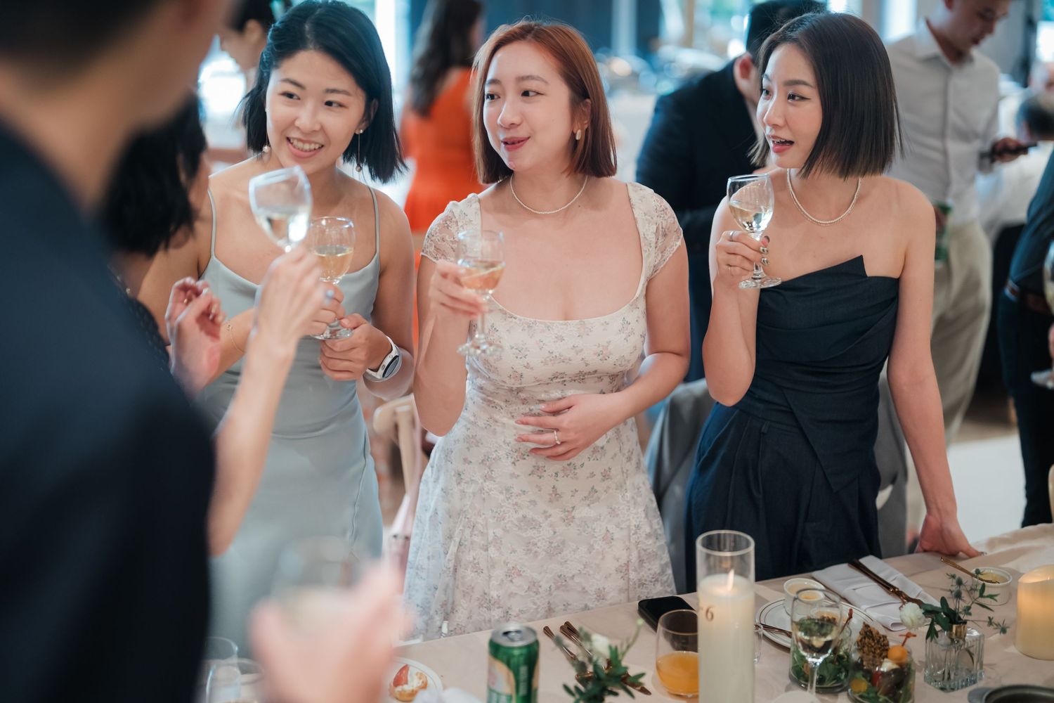 A group of wedding guests enjoying drinks and laughter during a celebratory reception gathering.