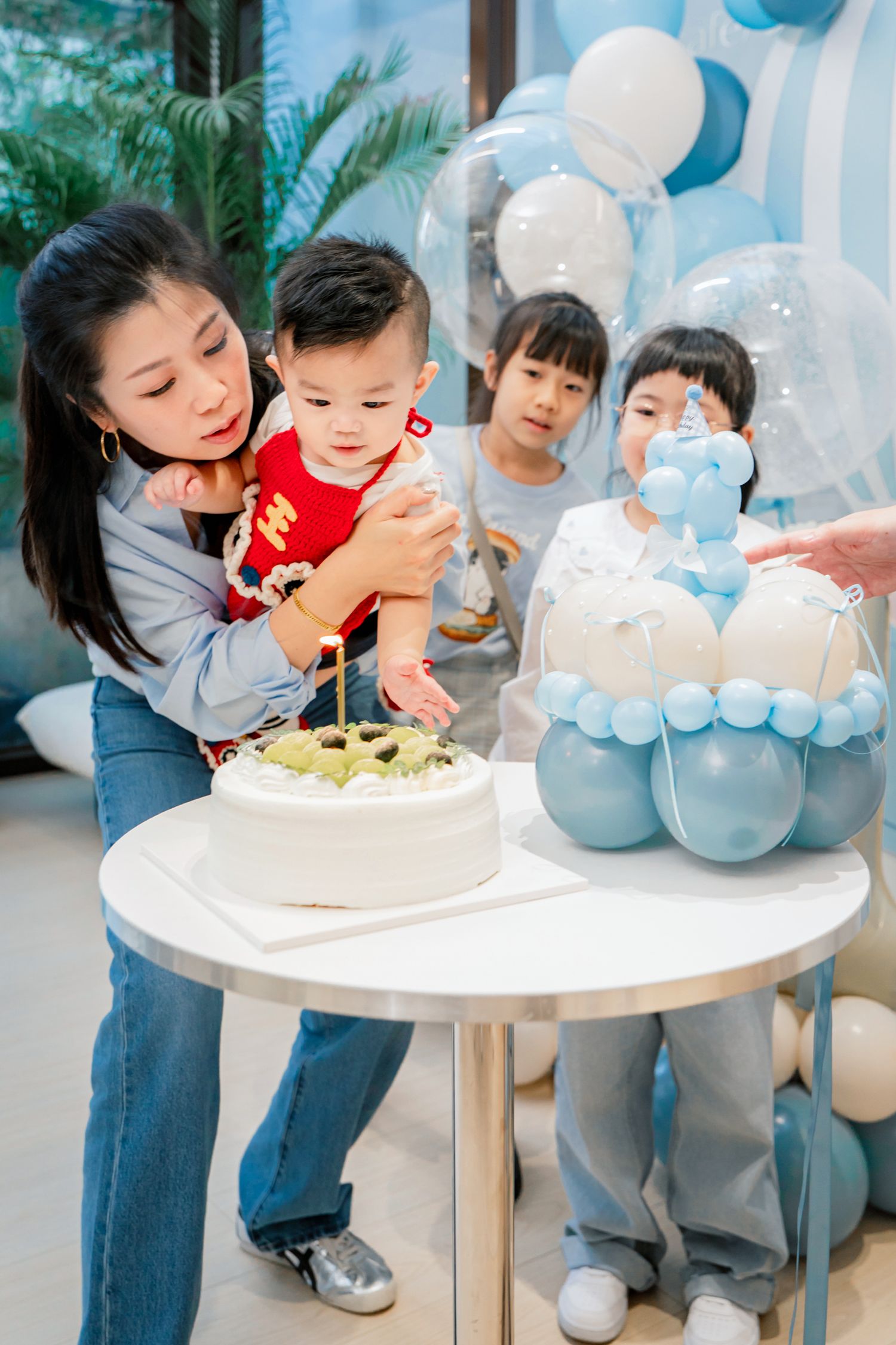 A series of photos showing a birthday celebration with blue balloons and white cake on a small round table.